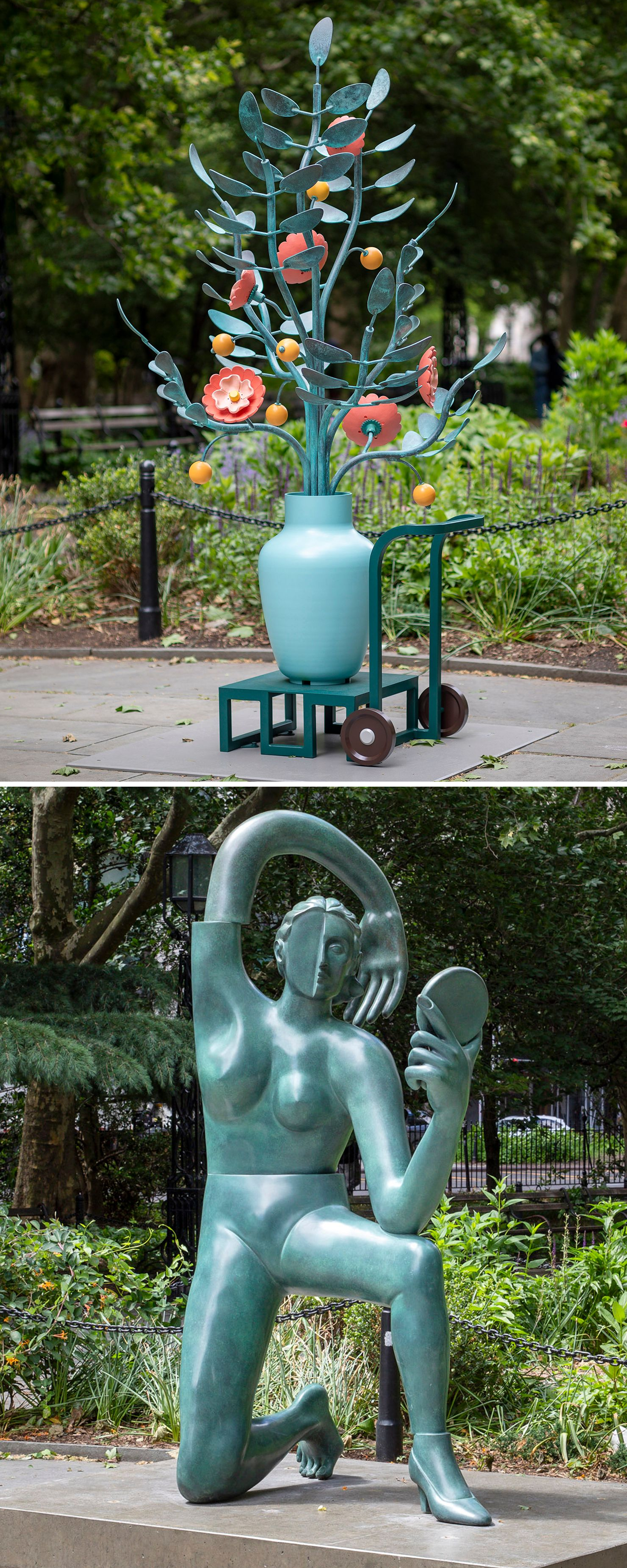 A large outdoor sculpture of a pale blue vase on a wheeled cart, holding oversized metal branches with coral flowers and yellow spheres, installed in a public park.; A large green patinated bronze sculpture of a stylized kneeling female figure holding a hand mirror, with her arm arching over her head, installed in a public park.