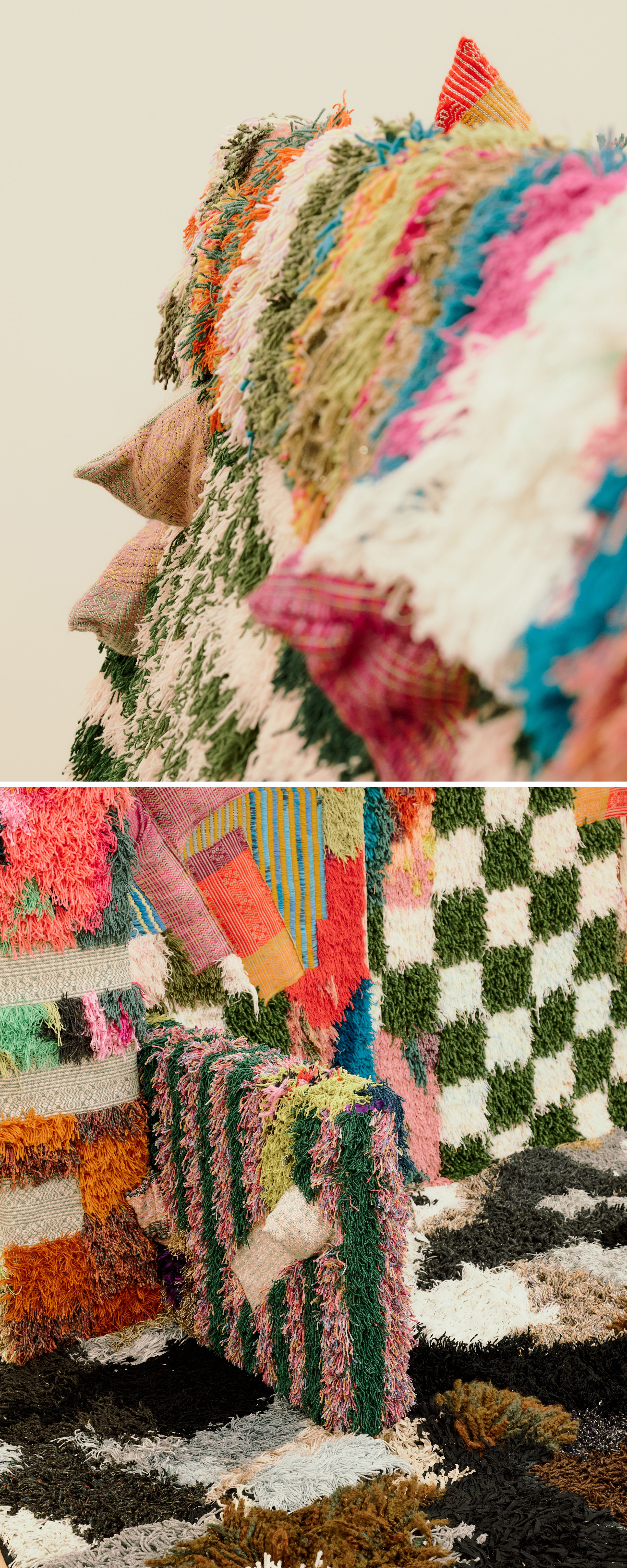 Close-up color photo of a textile artwork, showing dense bands of shaggy, multicolored yarn tufts in green, orange, pink, blue, and cream, with a few patterned woven fabric triangles projecting from the surface; Close-up of a textile installation, showing a shaggy multicolored fringe cascading over a striped and patchwork column, beside a green-and-white checkered panel and black-and-white patterned rugs on the floor