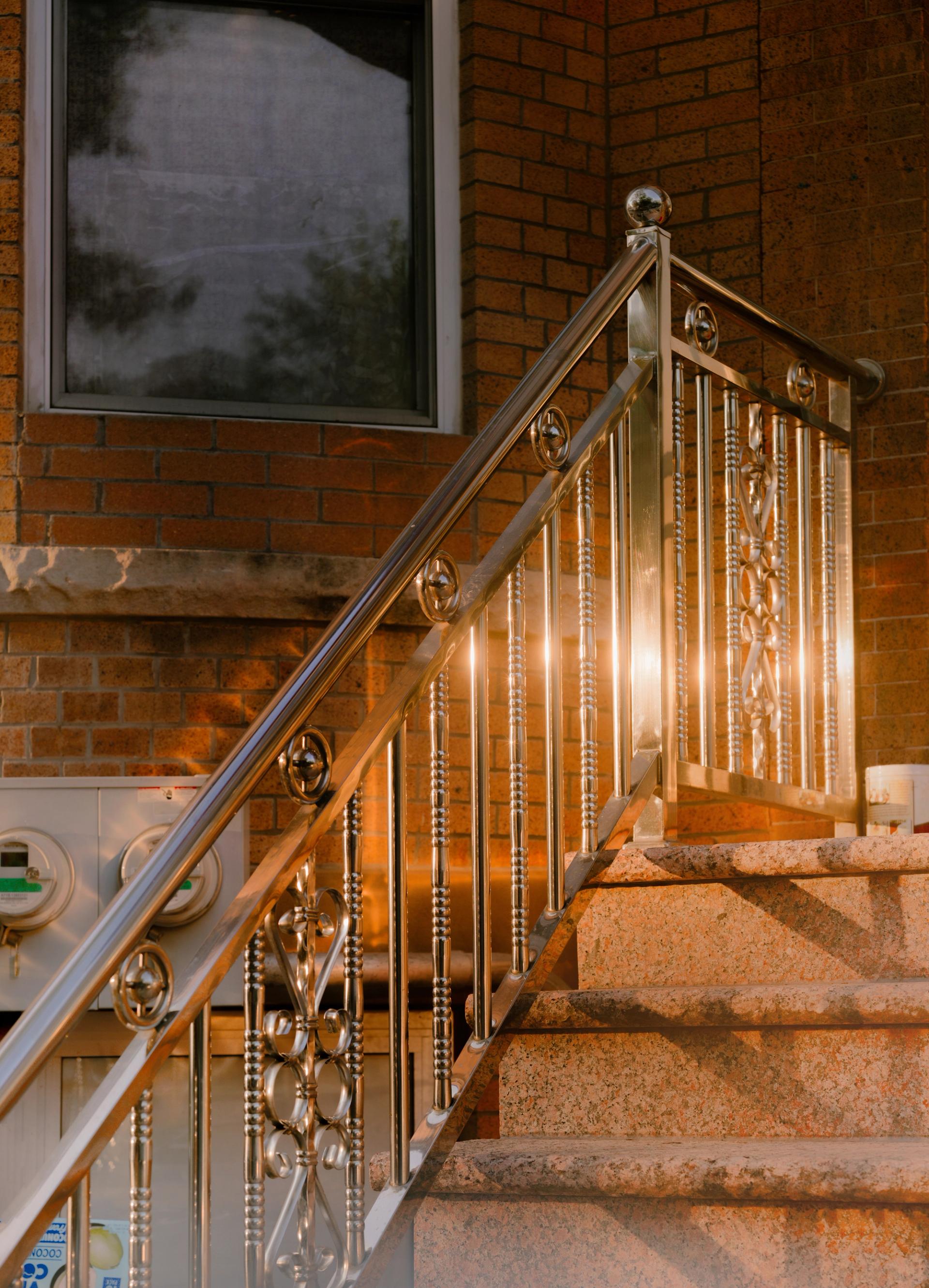 A chrome fence detail on an exterior staircase glints in the sun.