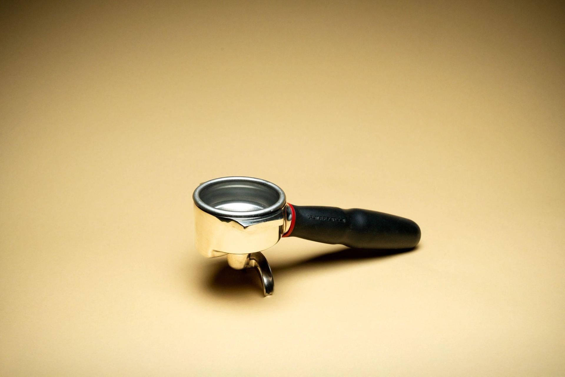 Espresso portafilter displayed against a yellow background.