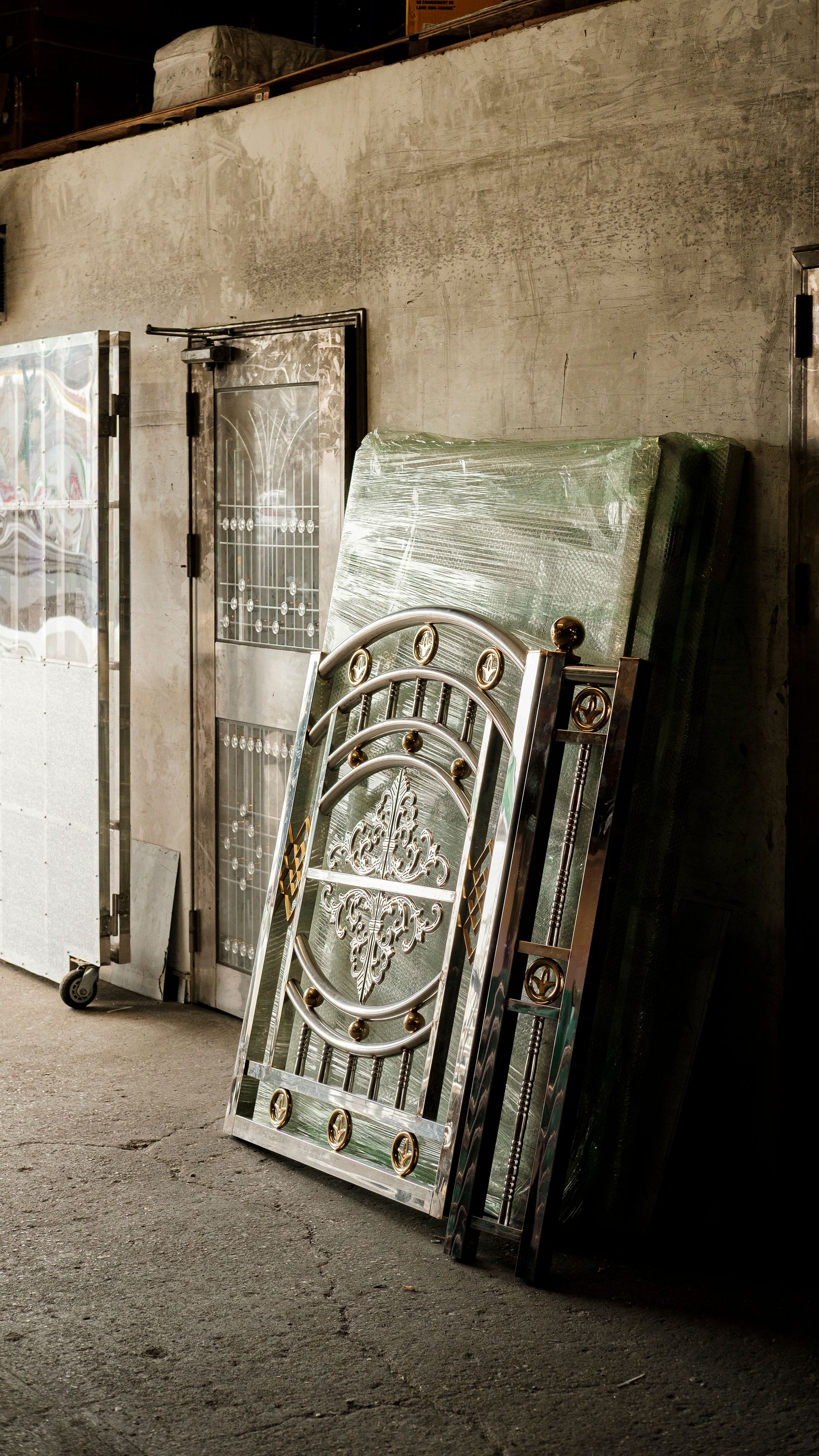 A stainless steel fencing panel leans against a concrete wall in the Brooklyn Stainless Steel workshop.