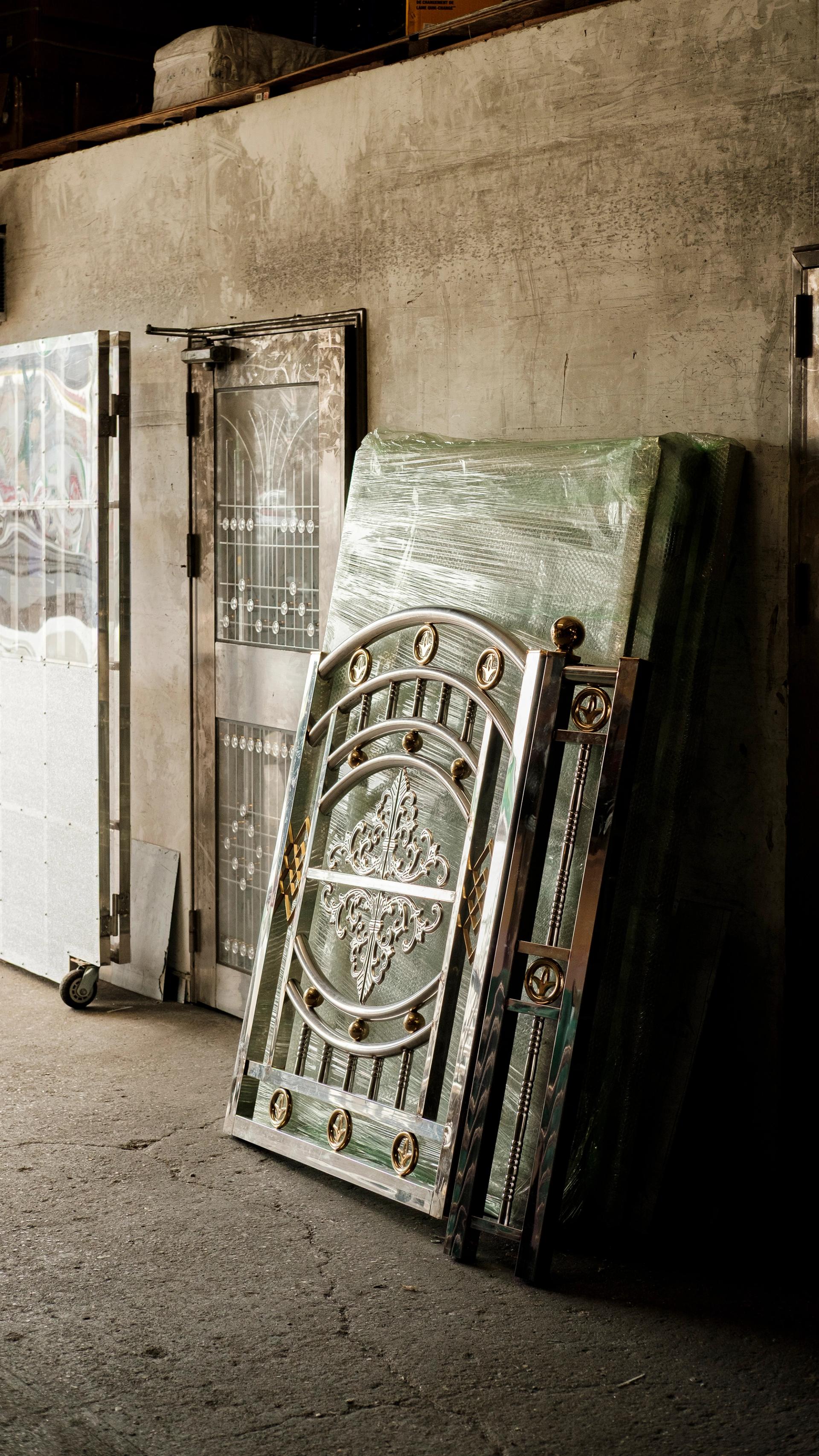A stainless steel fencing panel leans against a concrete wall in the Brooklyn Stainless Steel workshop.