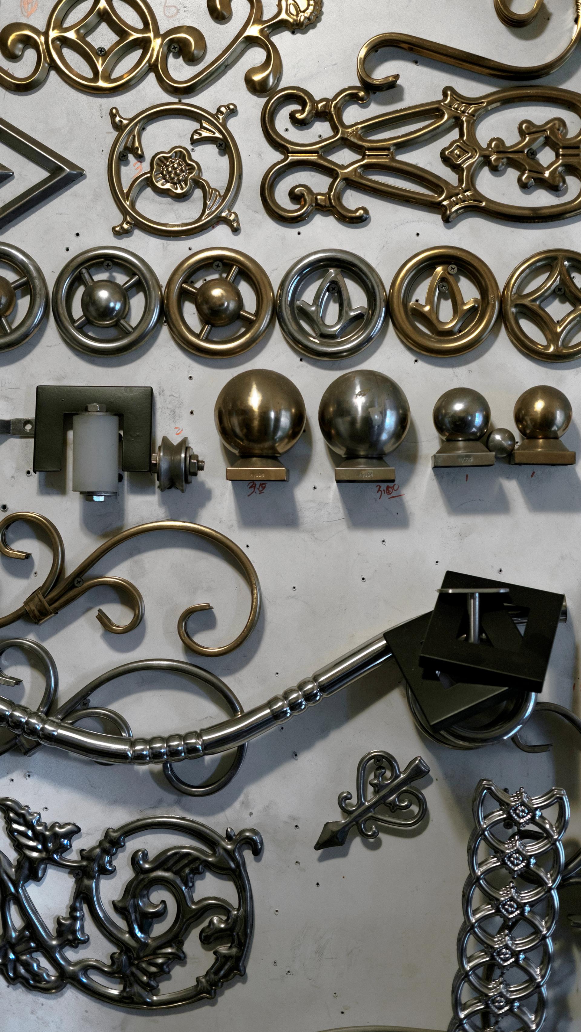 An array of stainless steel finials laid out on a beige surface.