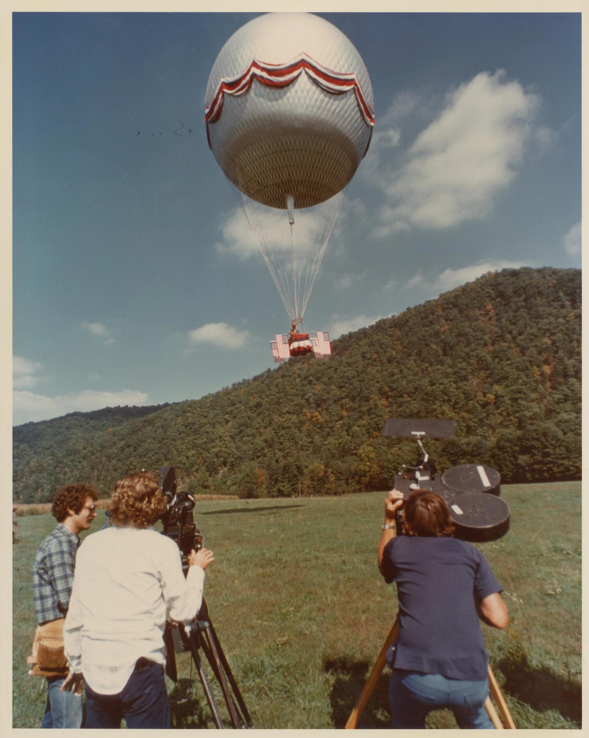 People behind the camera filming a hot air ballon. 