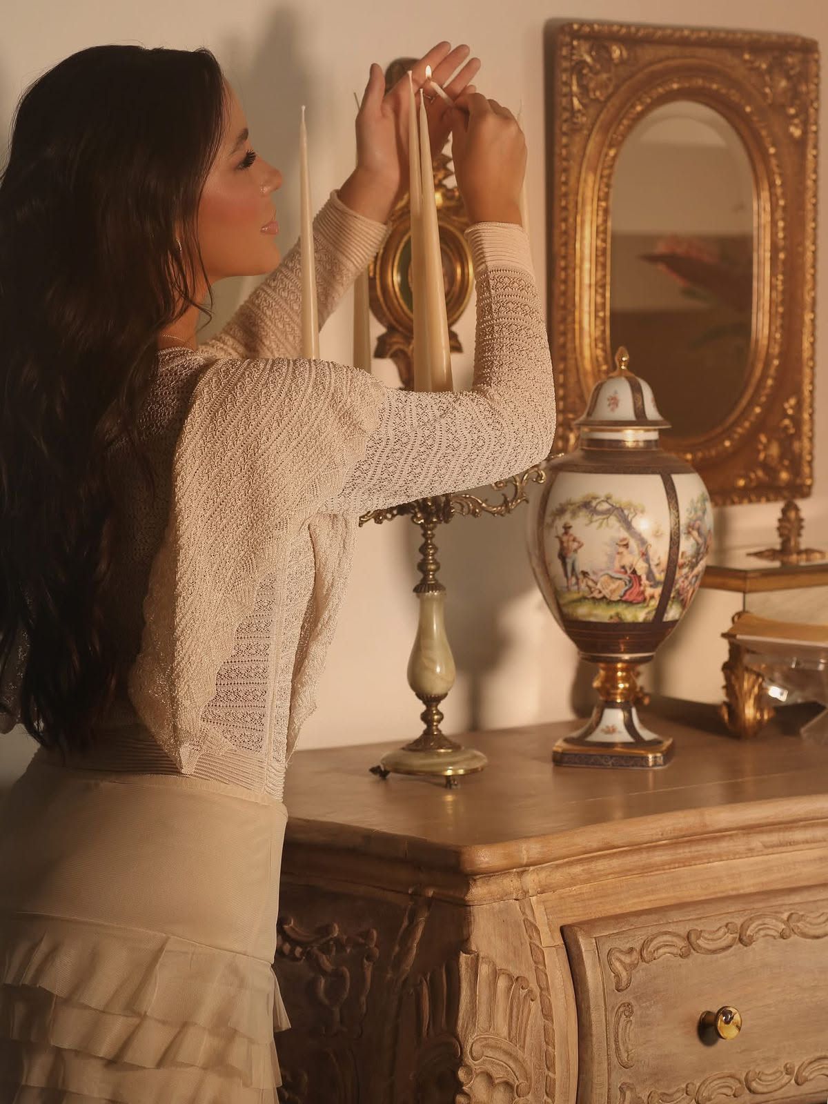 Iasmin acendendo velas diante de um espelho antigo