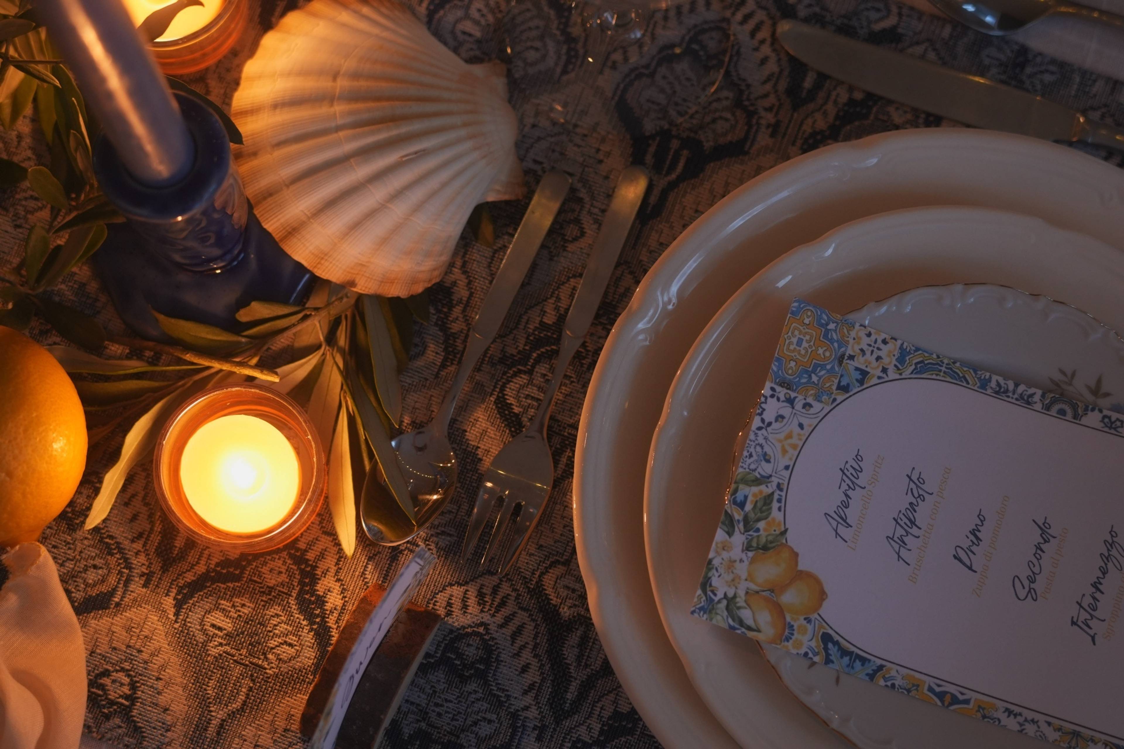 Tablescape detail — scallop shell, candle and silverware on paisley fabric
