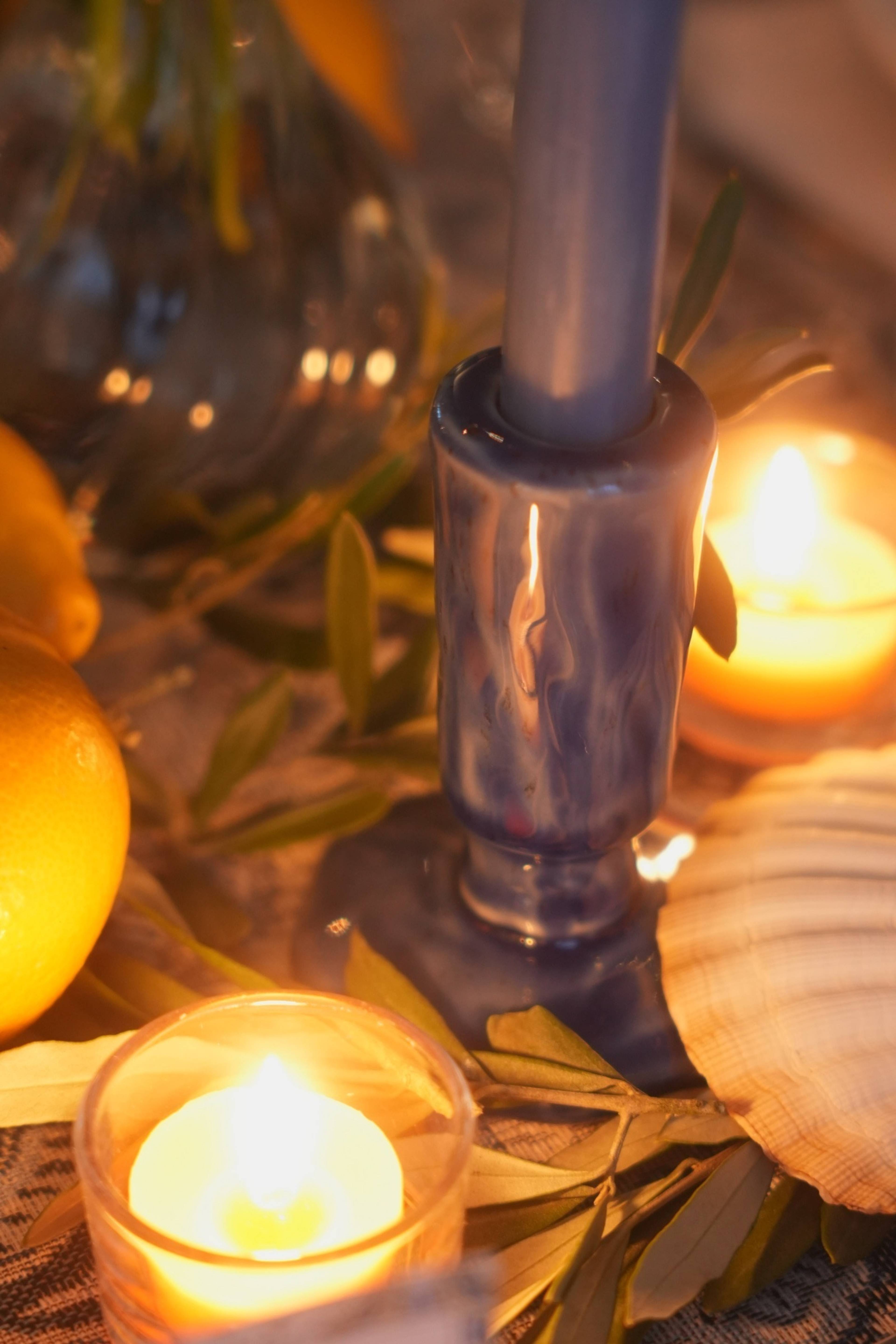 Candle close-up with shells, lemons and olive leaves