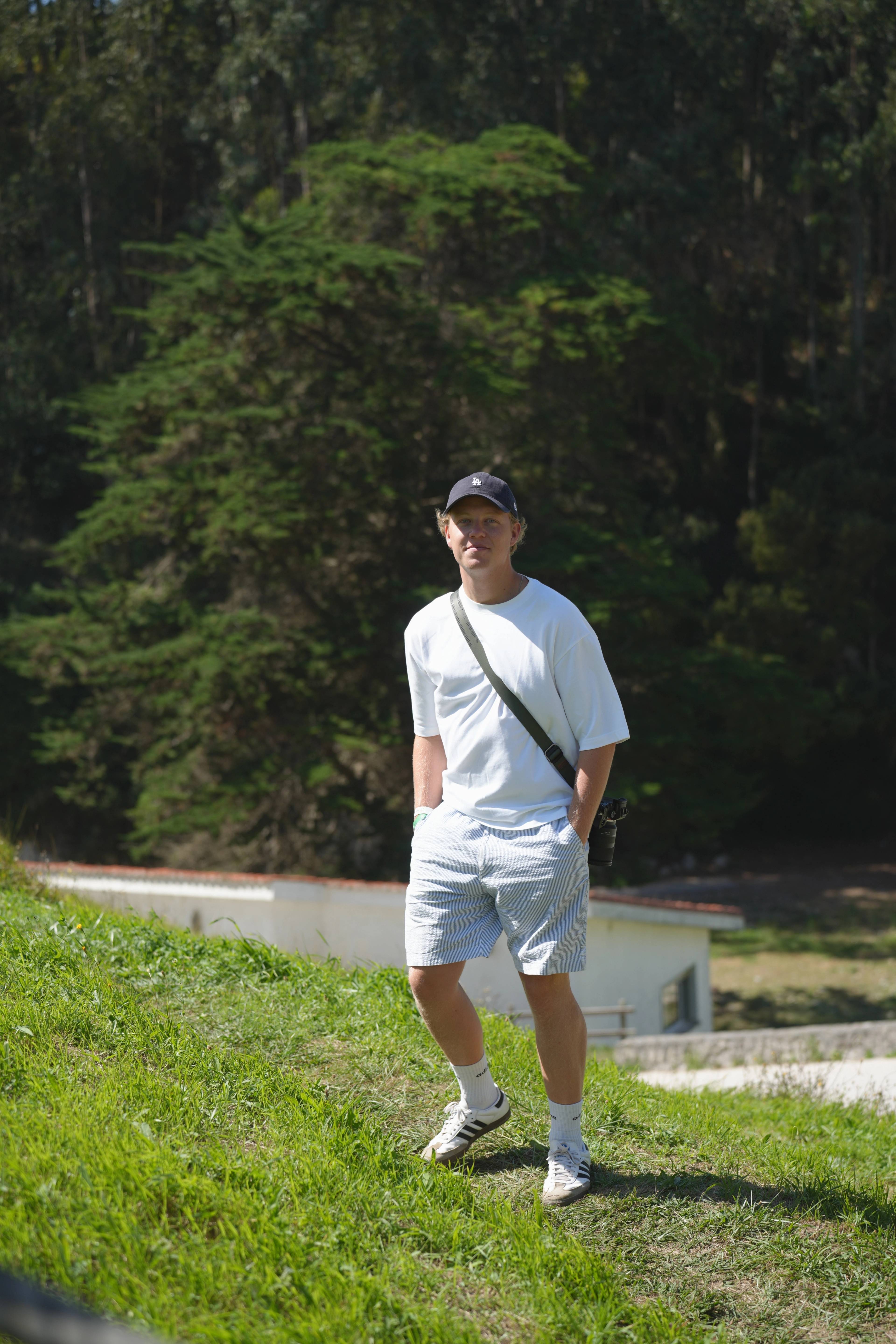 Walking up the slope through the green camp, cap and crossbody bag
