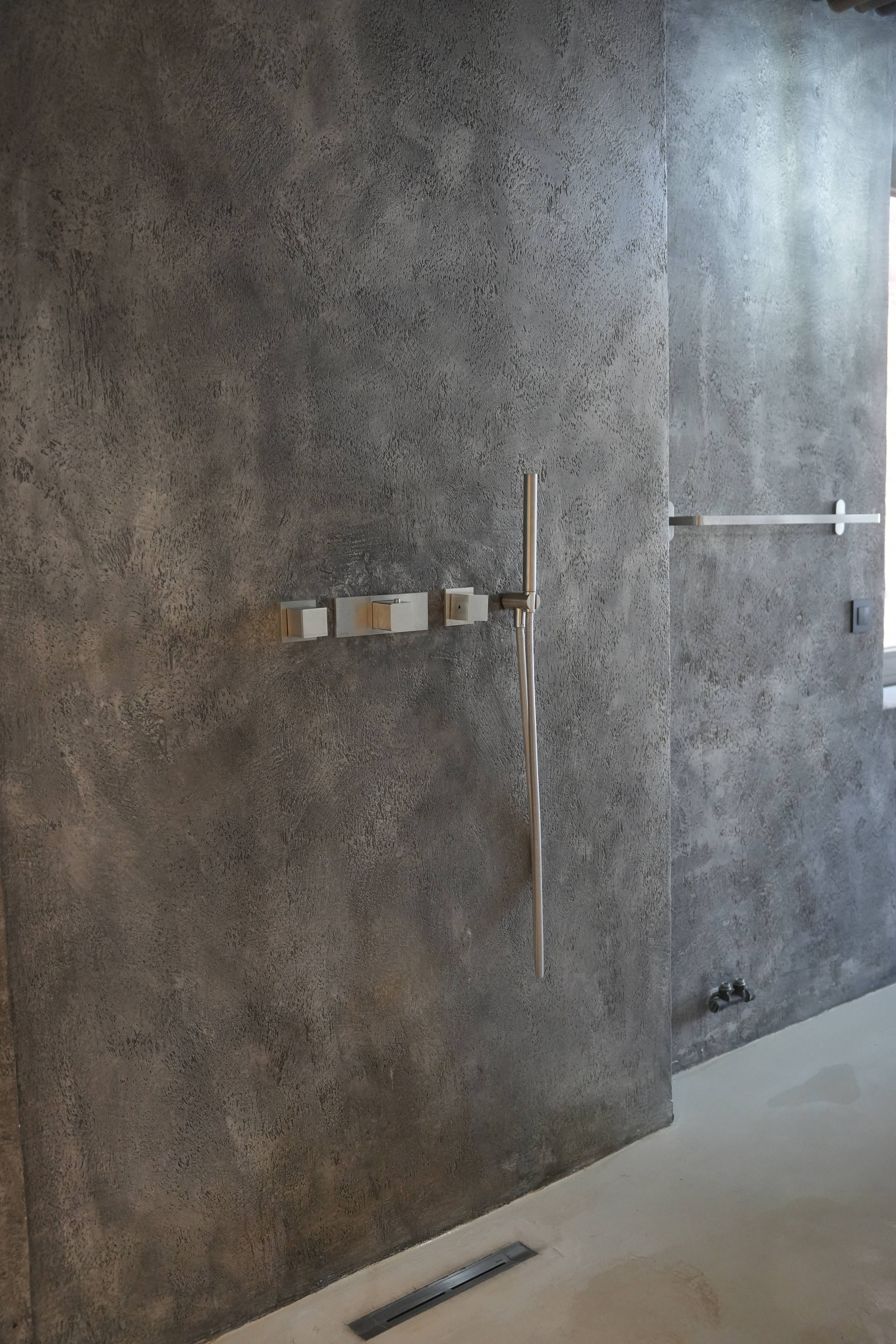 Polished concrete wall of the shower, brushed-brass fittings