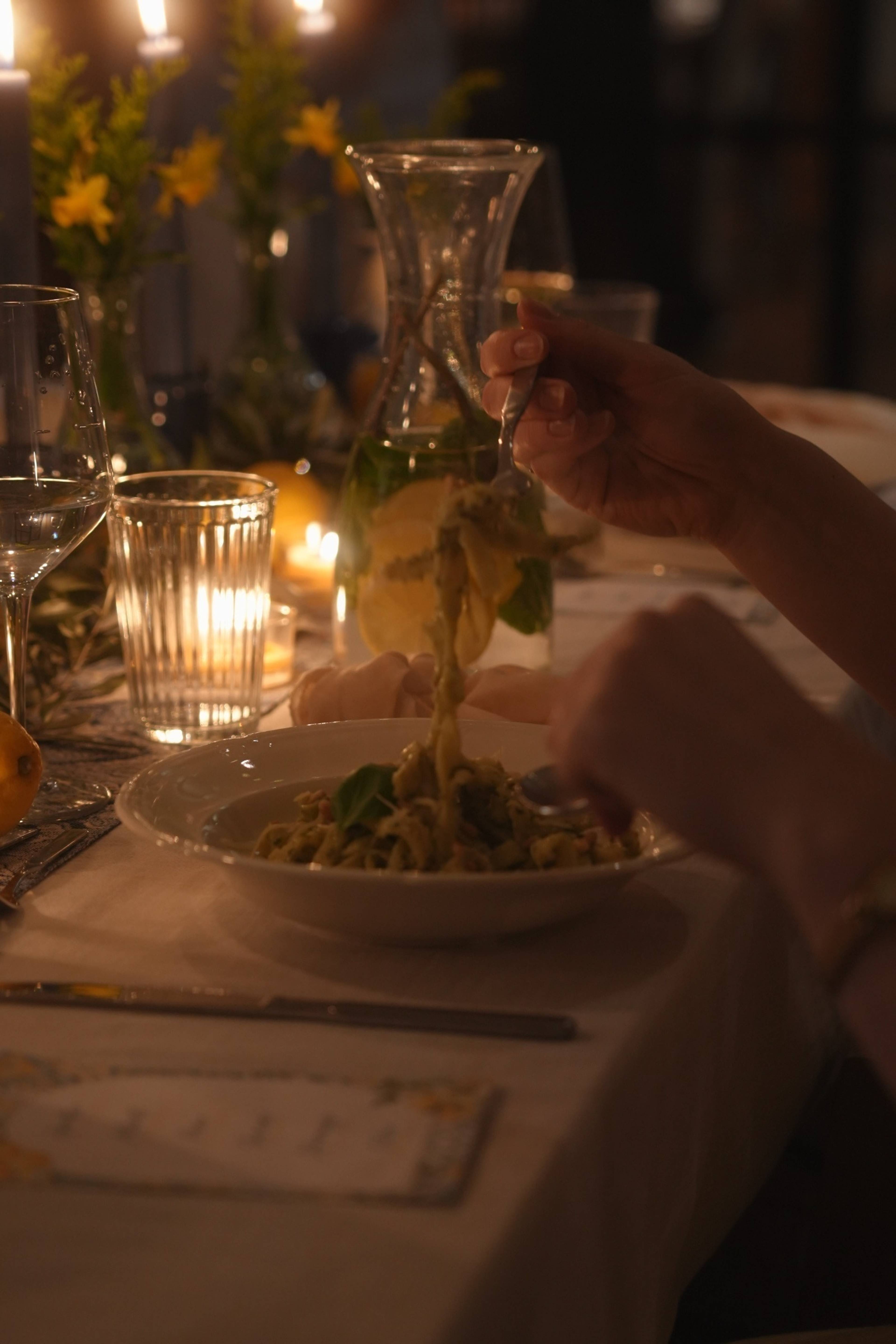 Pouring pesto over a bowl of fresh pasta