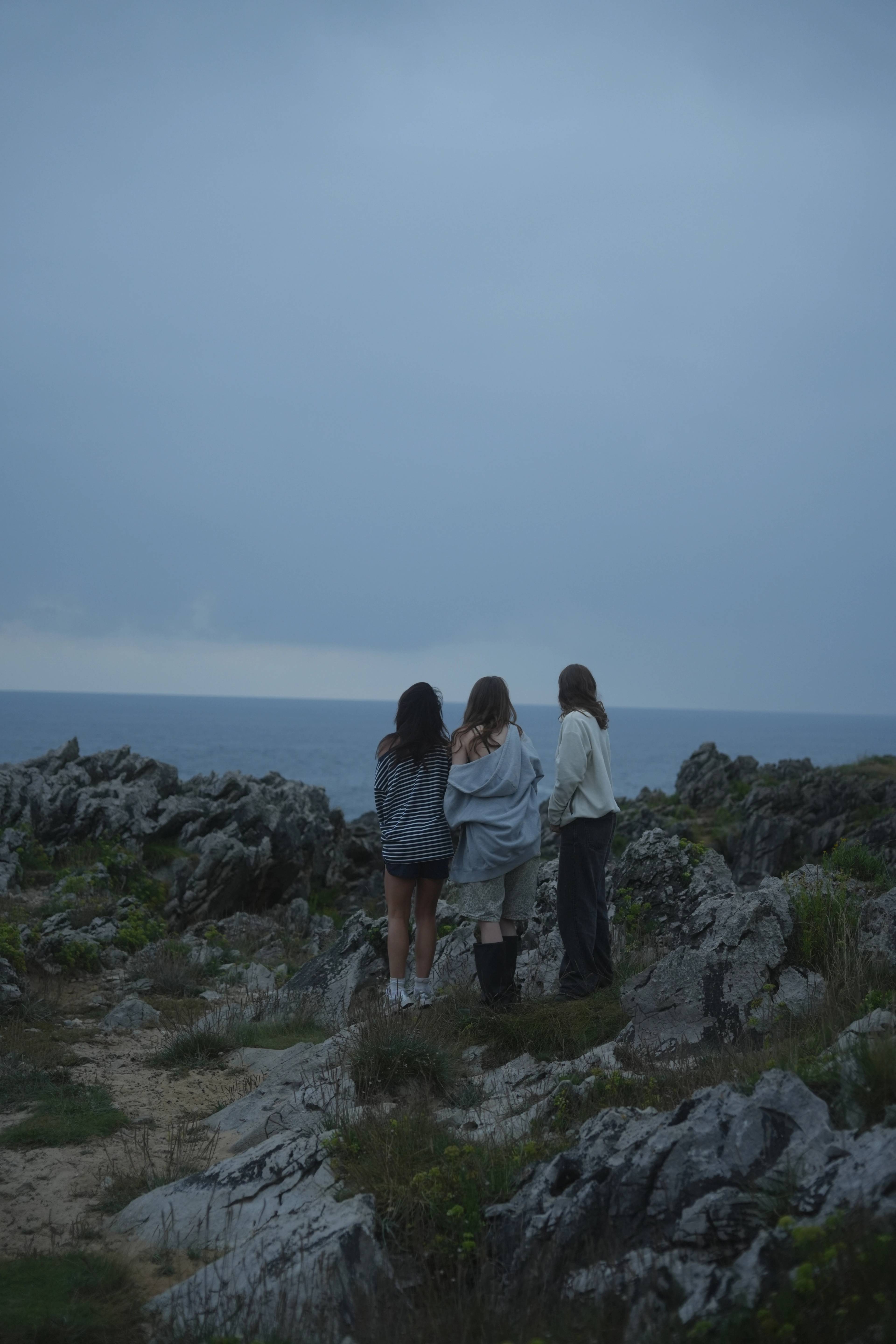 Three of us on the rocky cliffs at dusk, the ocean opening out below