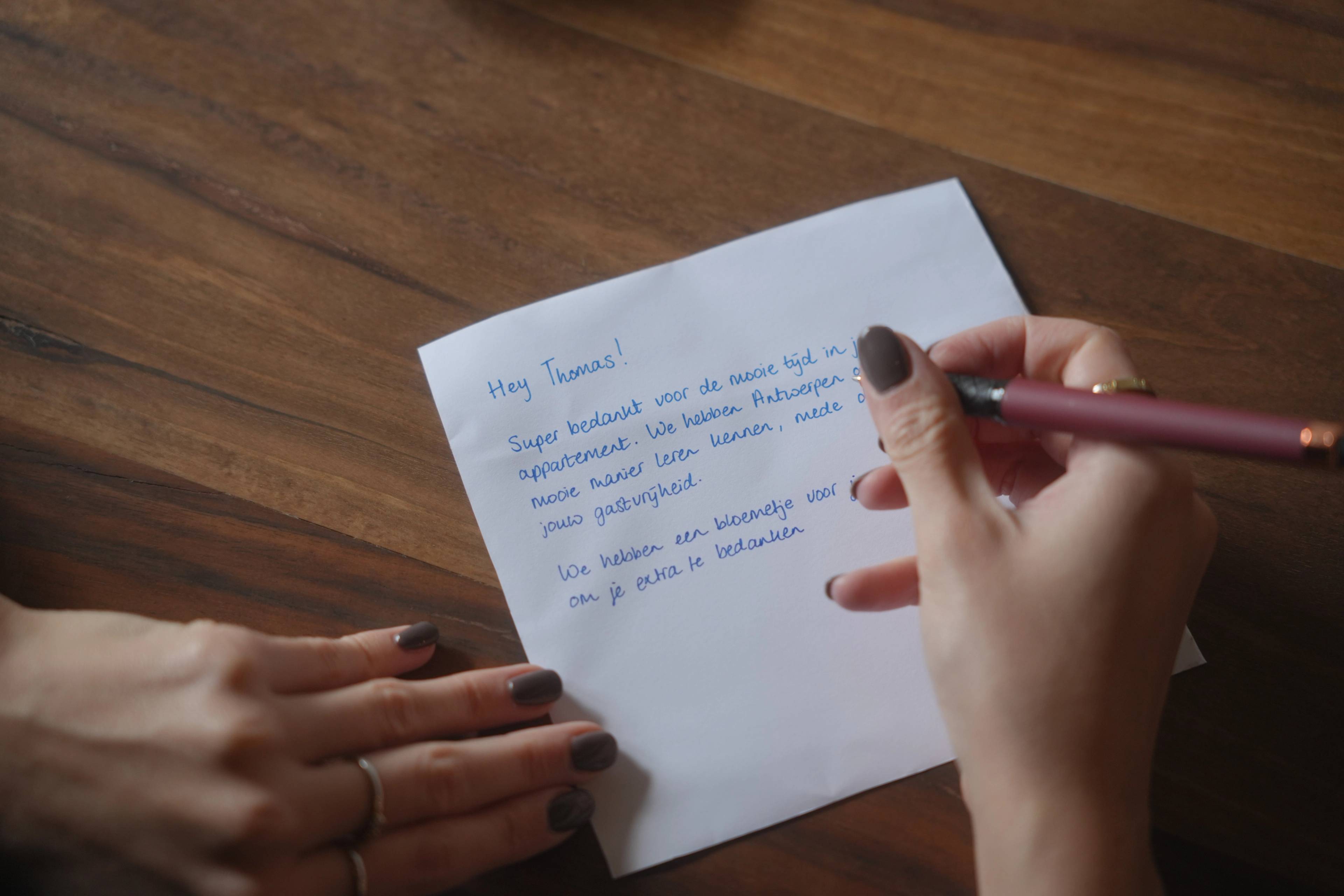 A handwritten thank-you note to Thomas, the host, on the wooden kitchen table