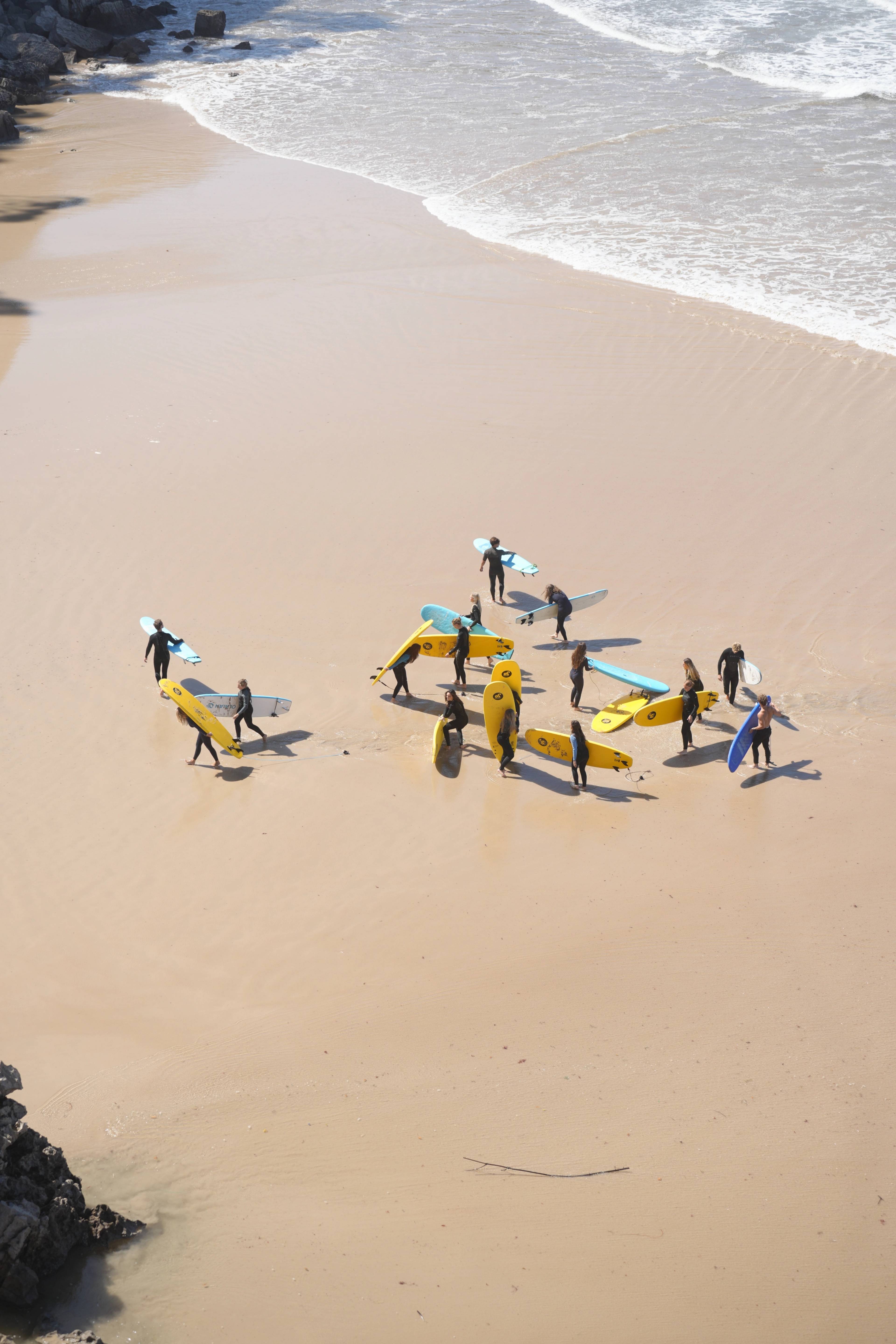 Coming out of the water in clusters, boards trailing in the sand