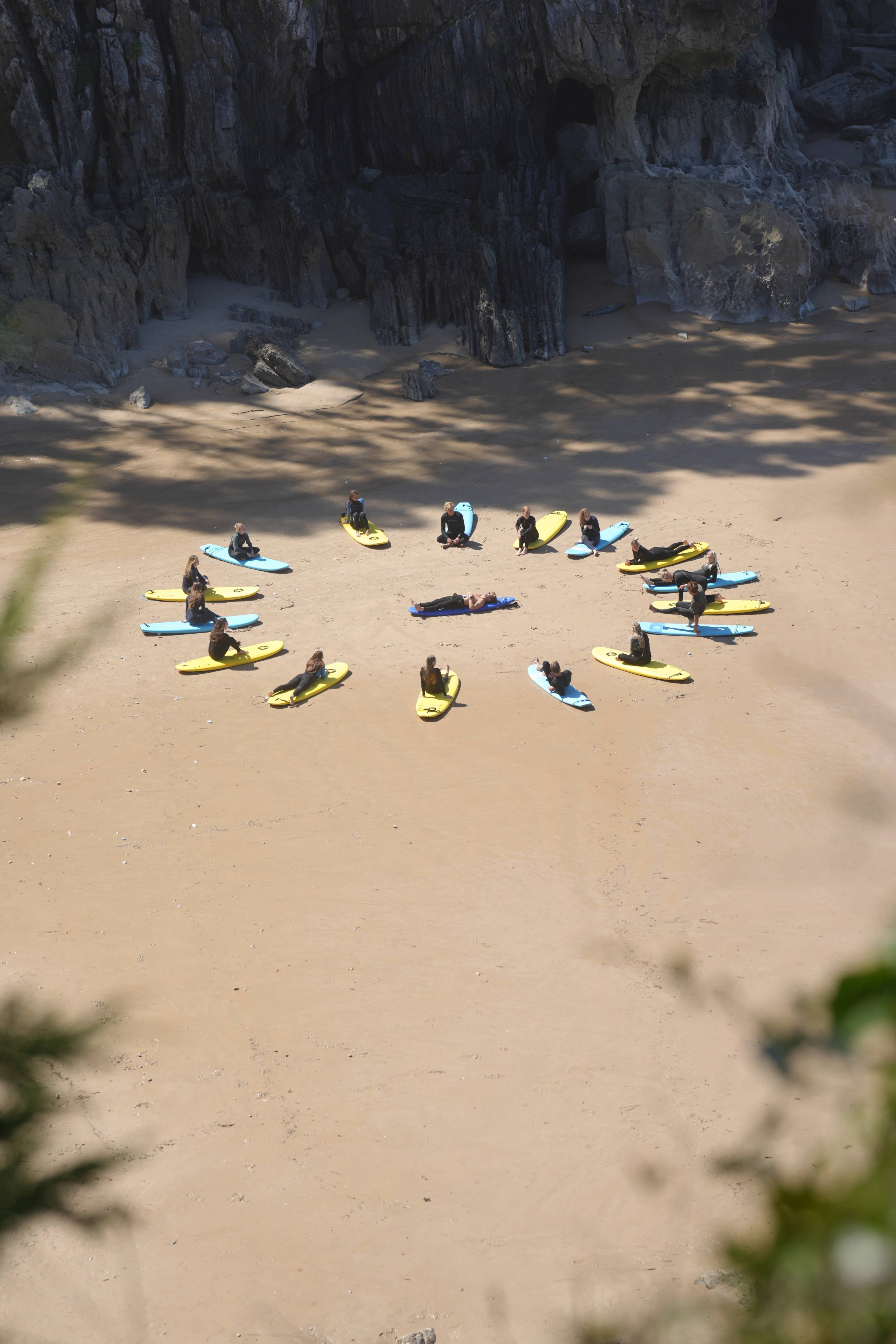 Surf class sat in a ring on the sand, cliffs framing the cove
