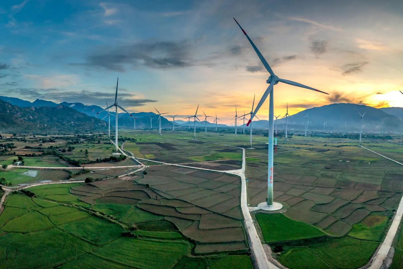 Wind turbines across farmland at sunrise