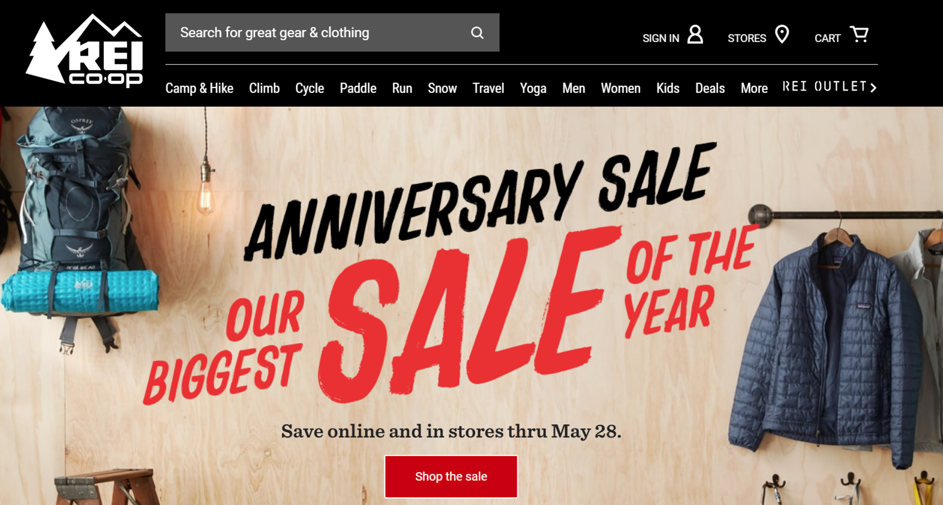 Display of outdoor gear and apparel featured in REI's Anniversary Sale, including tents, backpacks, and hiking boots.