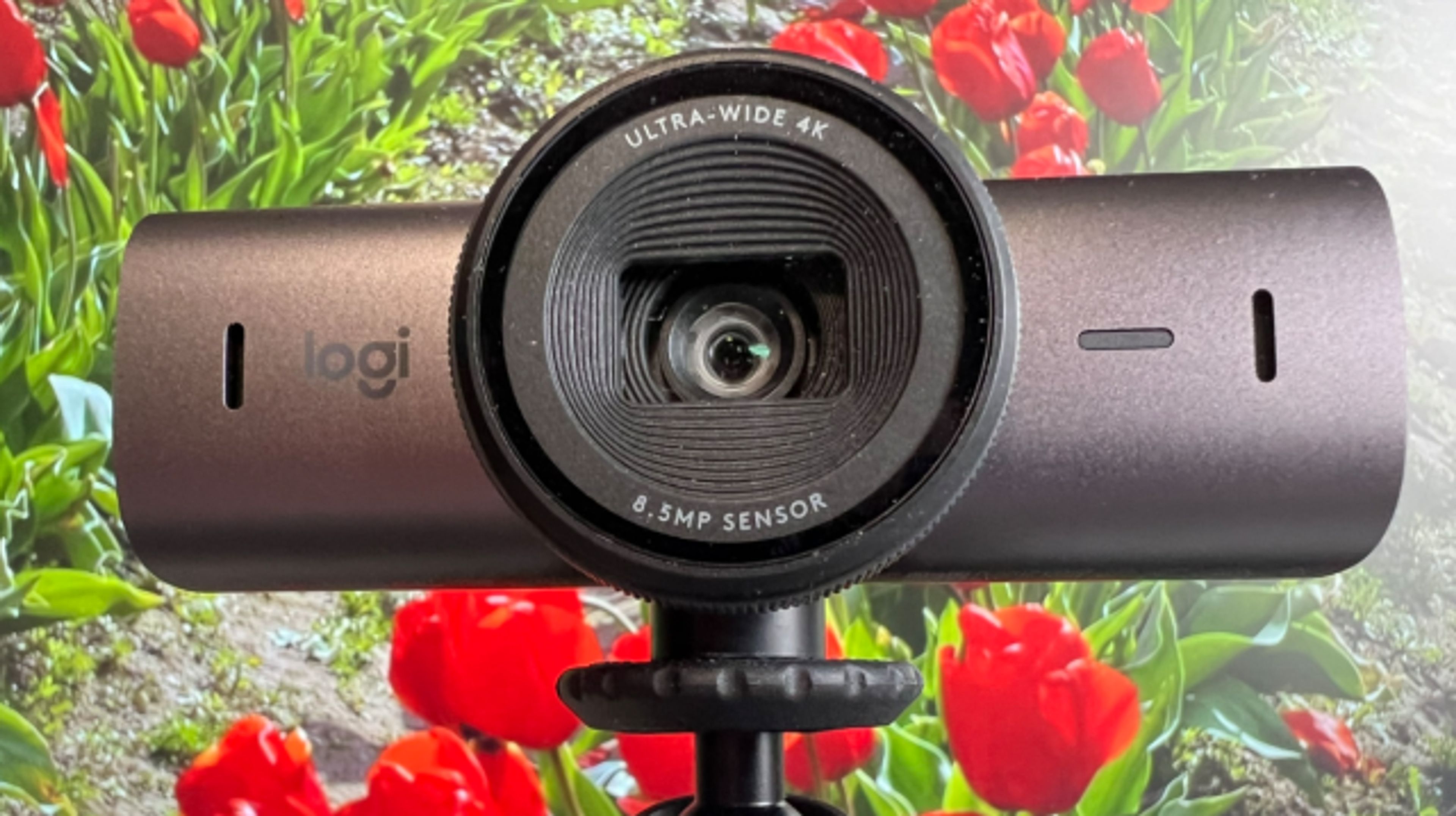 The Logitech Brio 705 webcam mounted on a monitor in a professional office setting, showing its sleek design and crystal-clear image capture.