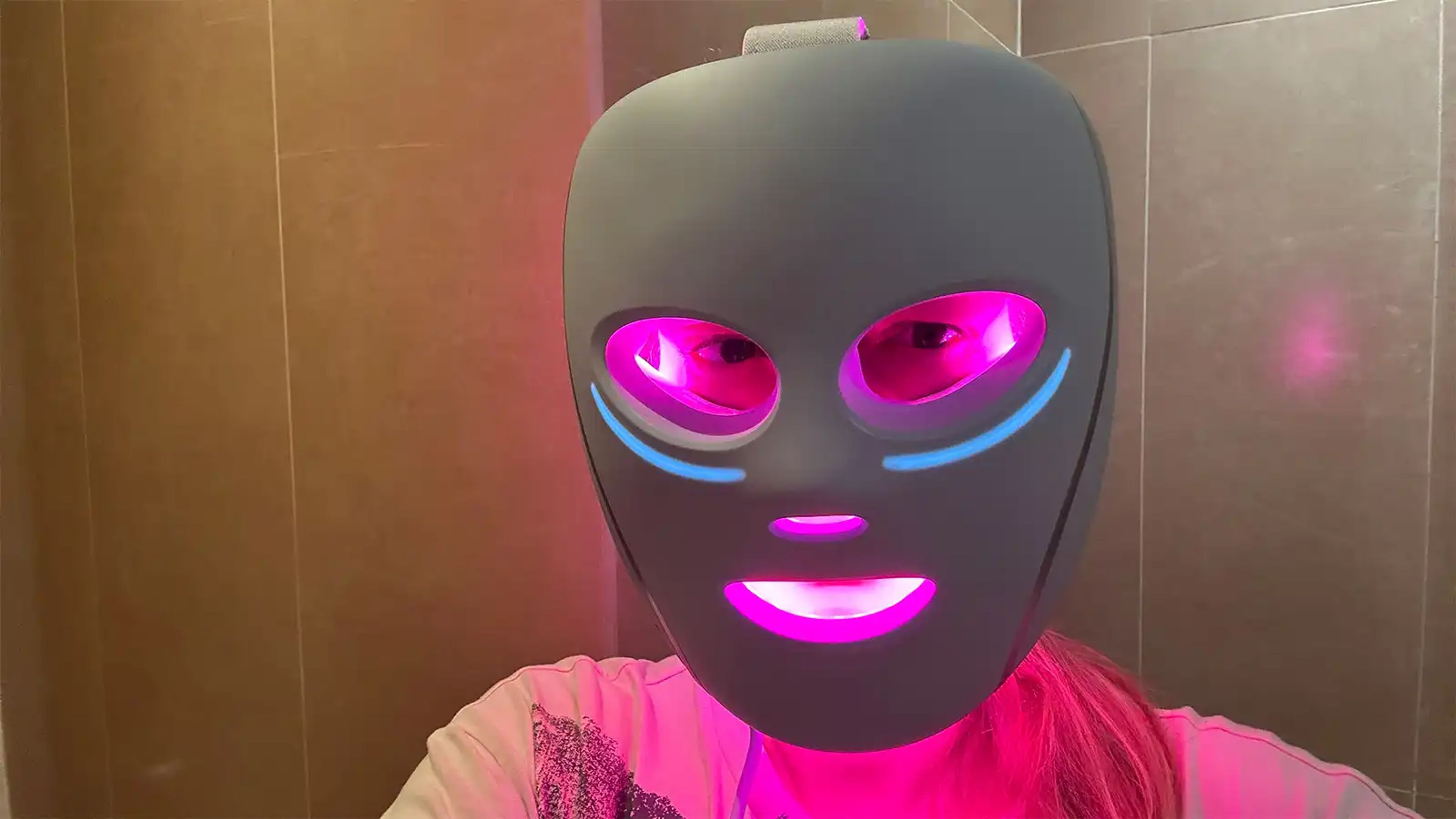 A person wearing the Shark CryoGlow LED face mask, showcasing its sleek design and under-eye cooling pads.