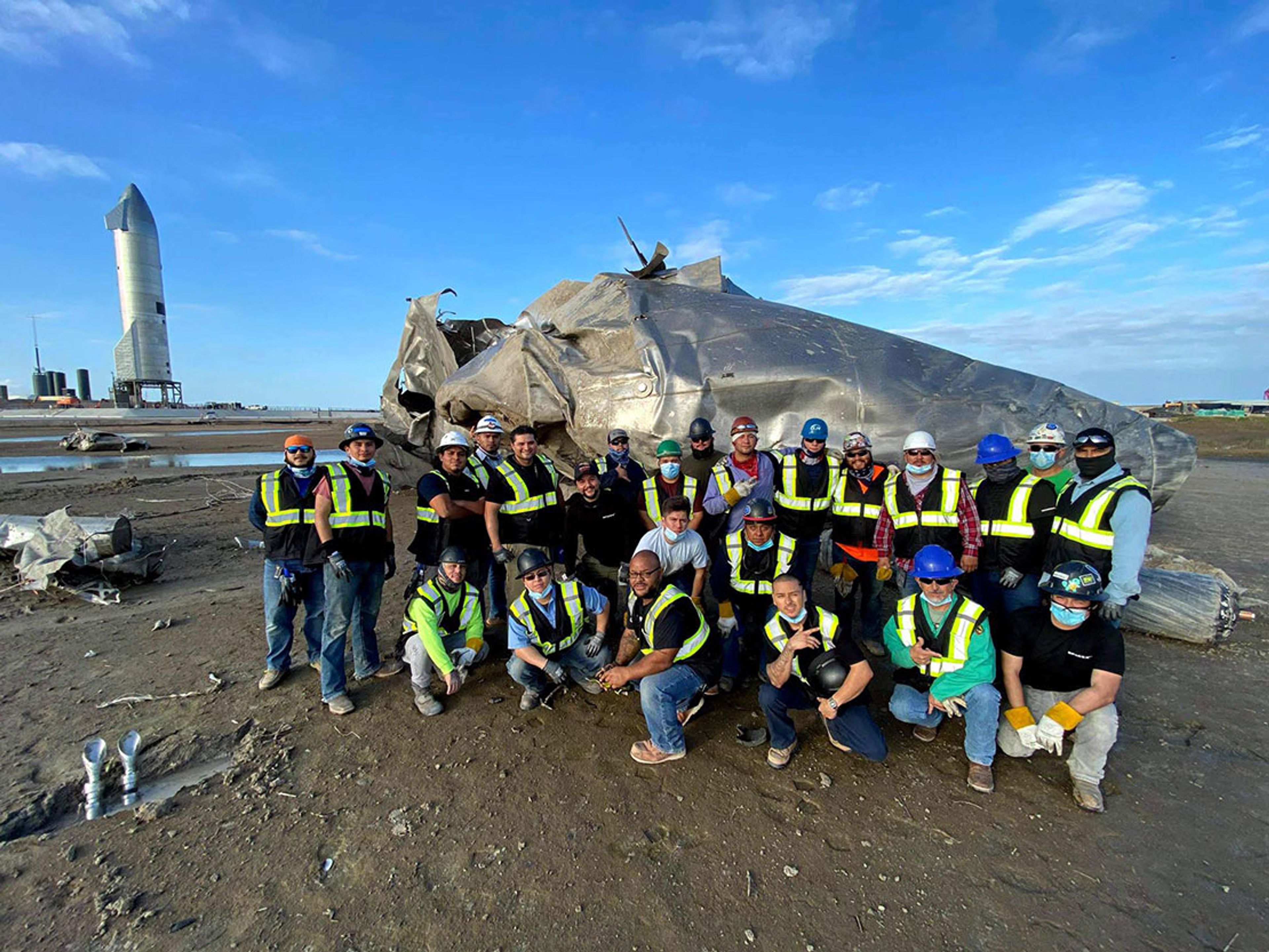SpaceX workers assembling spacecraft at Starbase with safety gear, surrounded by high-tech launch infrastructure and towering rockets.