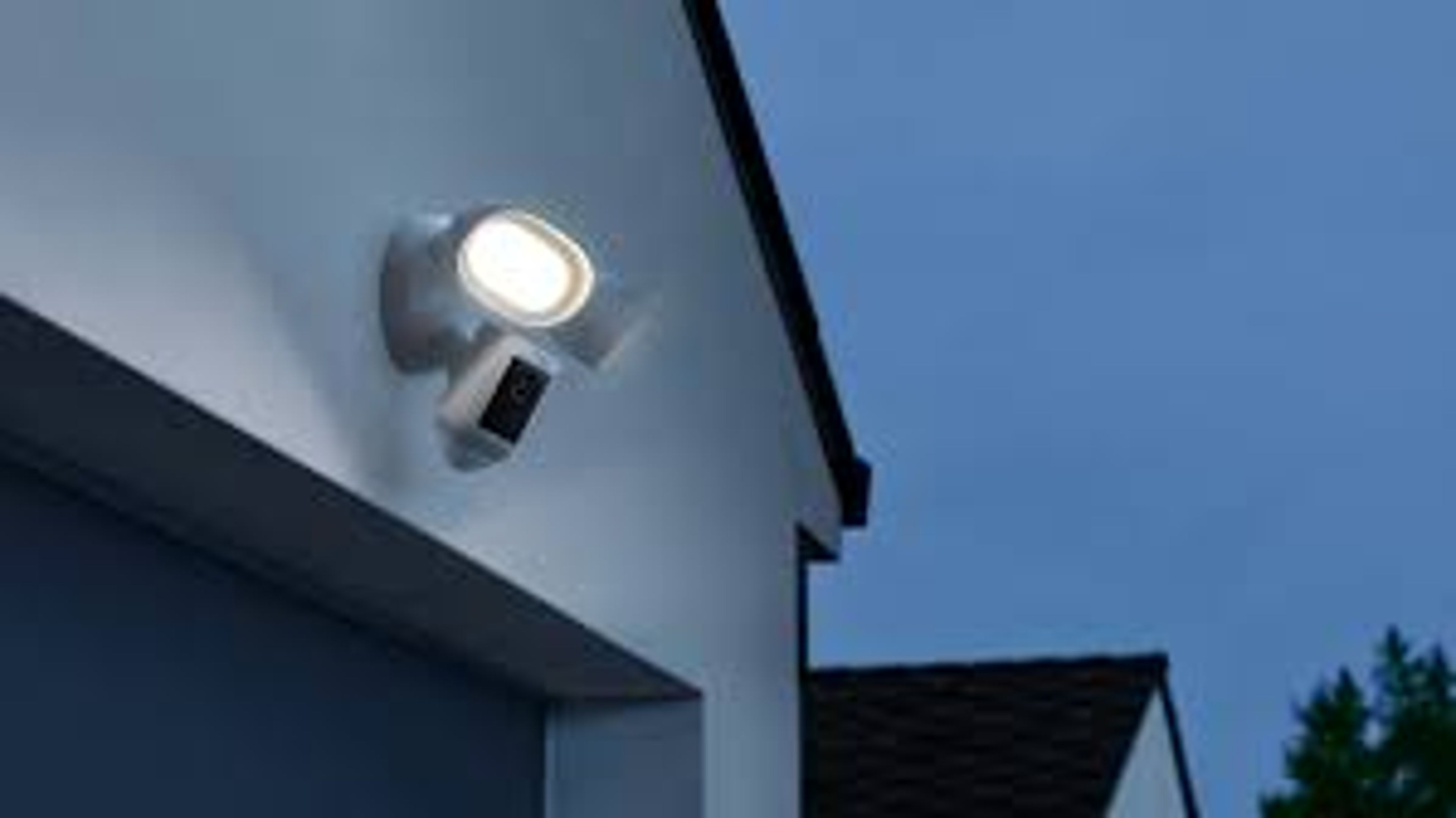 The Ring Floodlight Cam Wired Pro mounted above a garage, illuminating a driveway with motion detection and surveillance in action.
