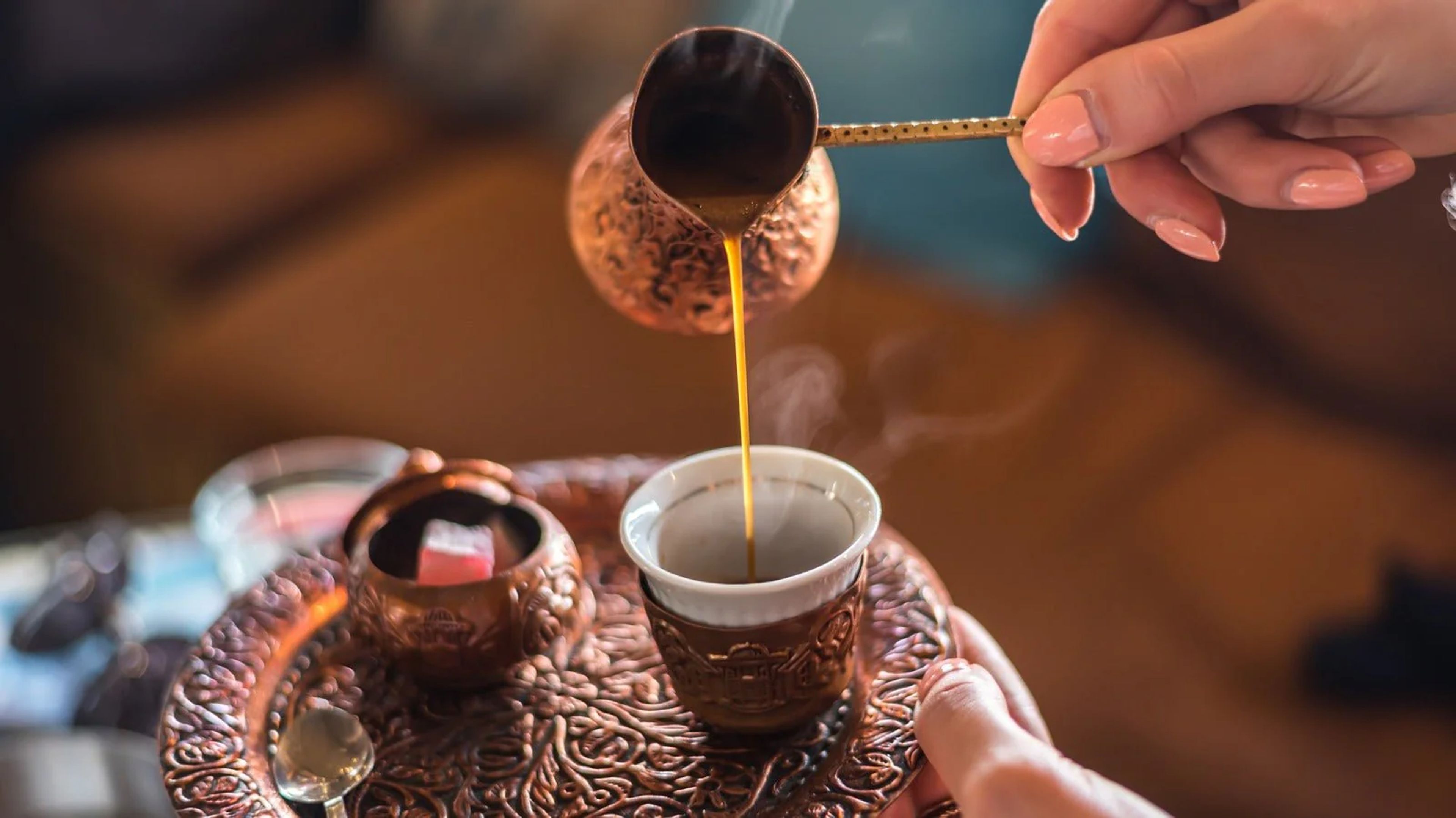 A traditional Turkish coffee cup with ornate patterns, surrounded by coffee grounds and a copper cezve, evoking a sense of rich heritage and aroma.