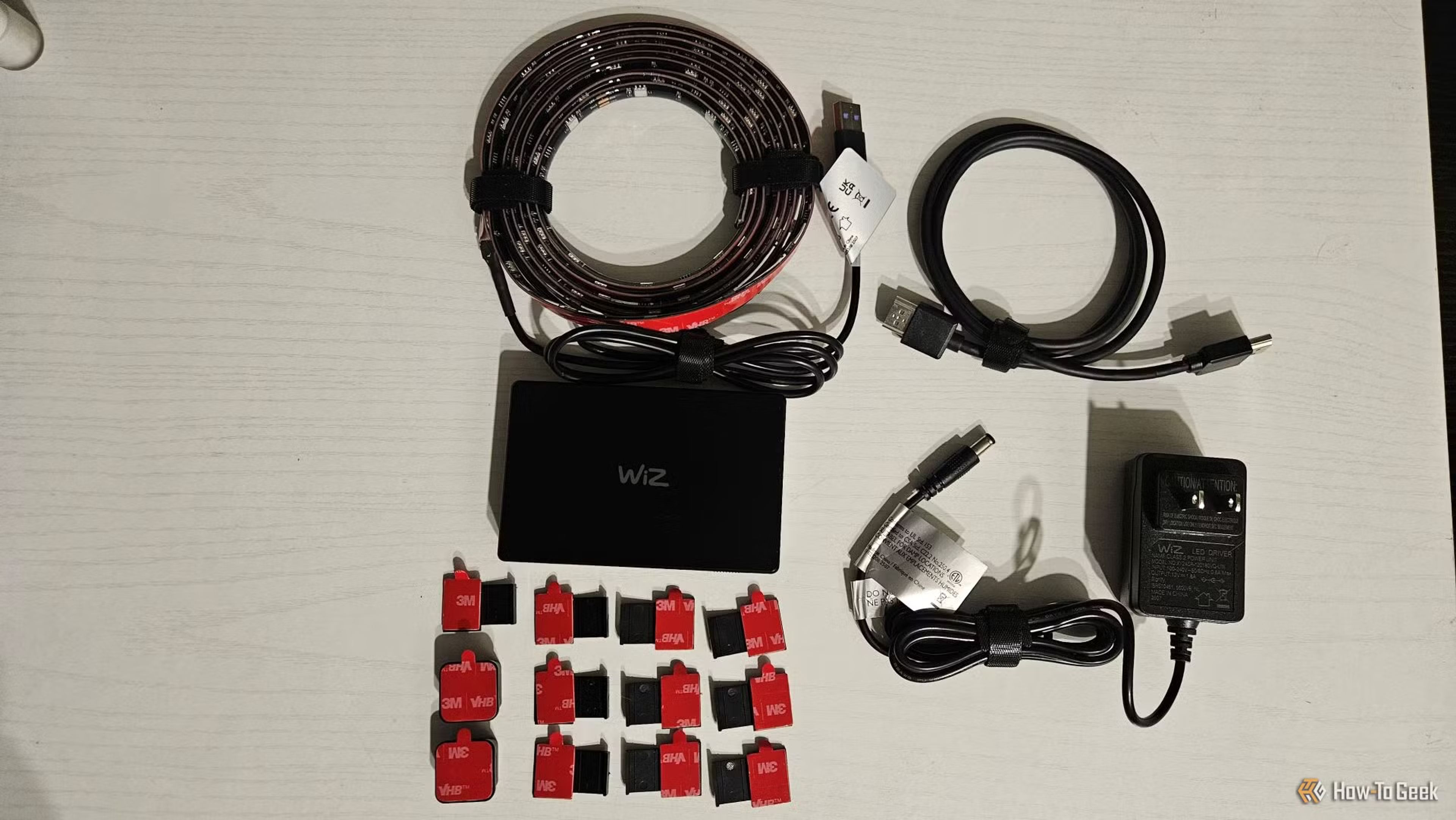 The WiZ HDMI Sync Box Kit installed behind a modern TV, casting dynamic backlighting that matches on-screen colors for an immersive viewing experience.