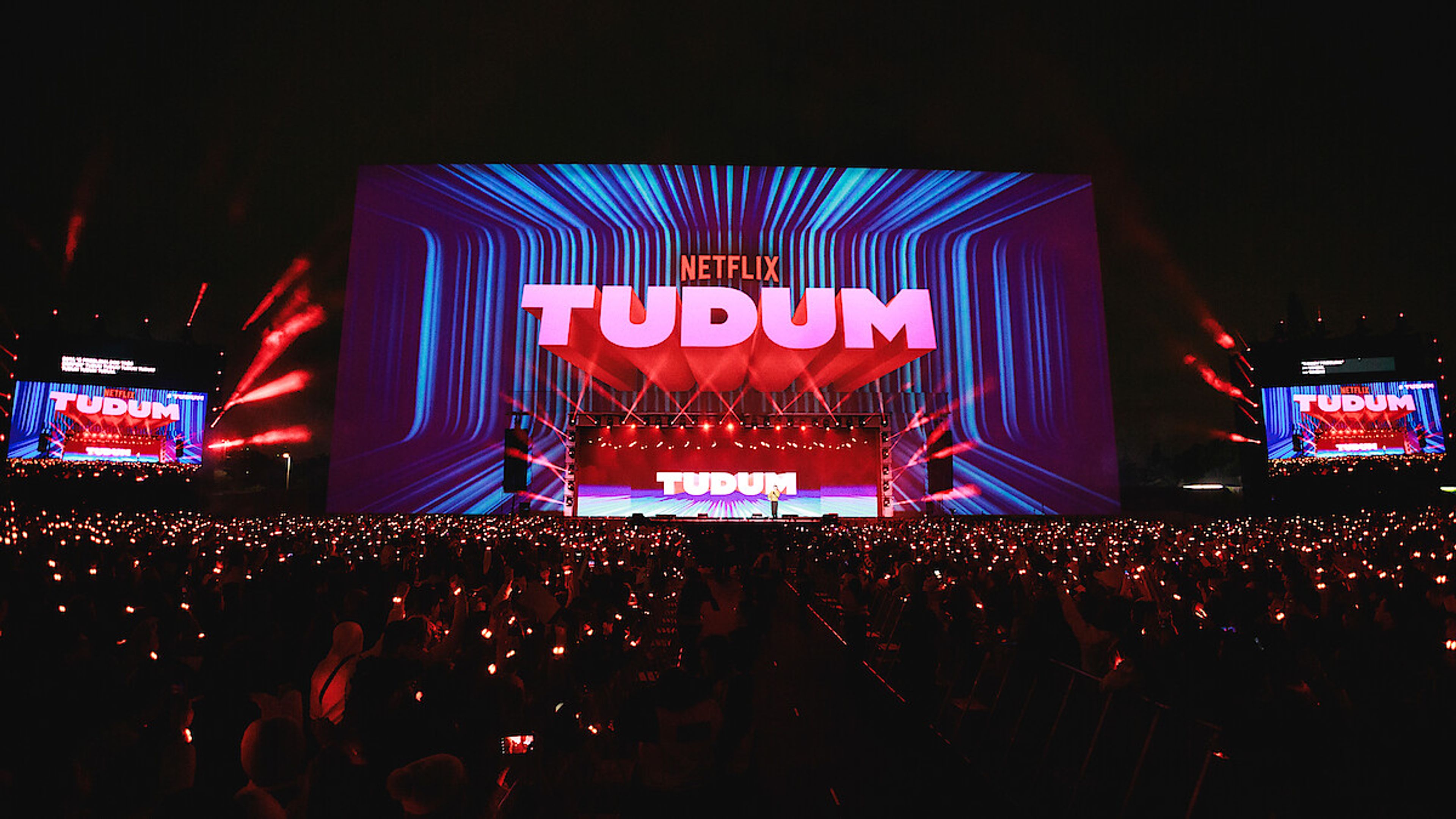 Netflix Tudum 2025 A vibrant stage lit with Netflix red and fan-favorite show banners, capturing the energy and anticipation of Tudum 2025.