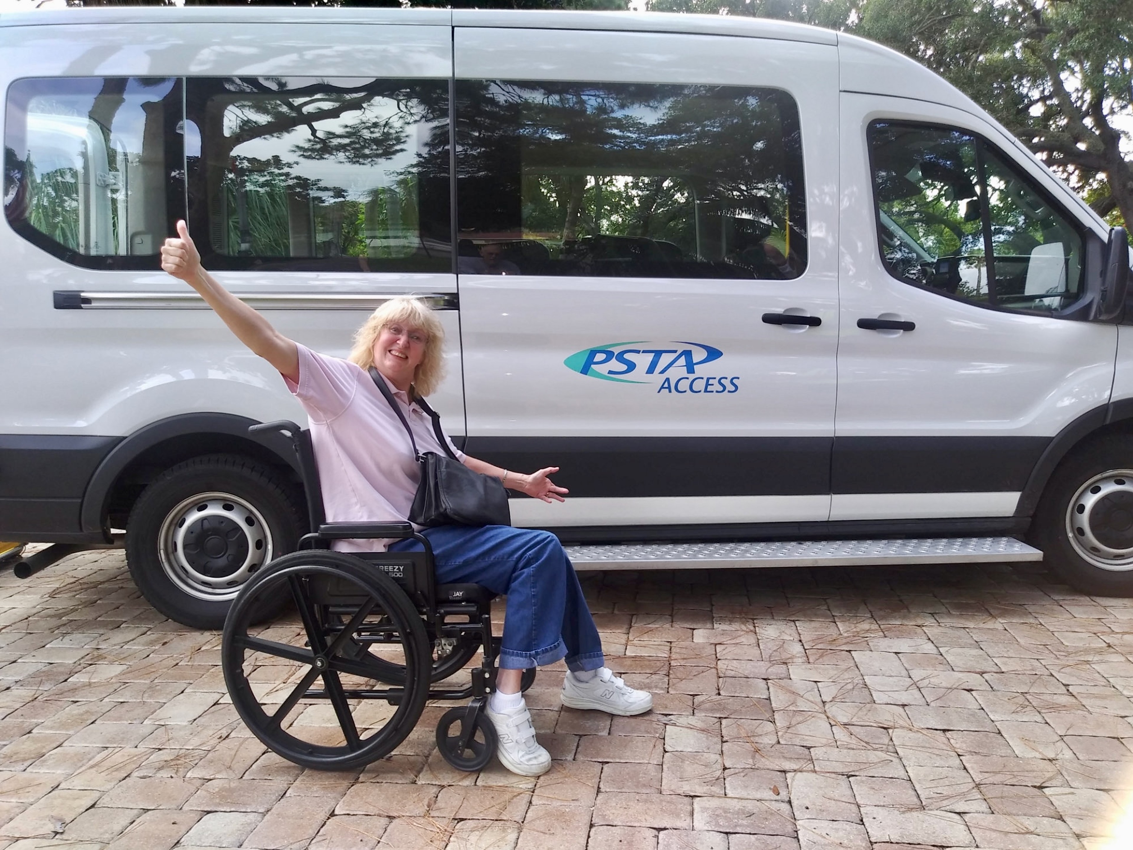 A photo of paratransit rider, Kim Rankine, in front of a PSTA Access Wheelchair Accessible Vehicle (WAV).  