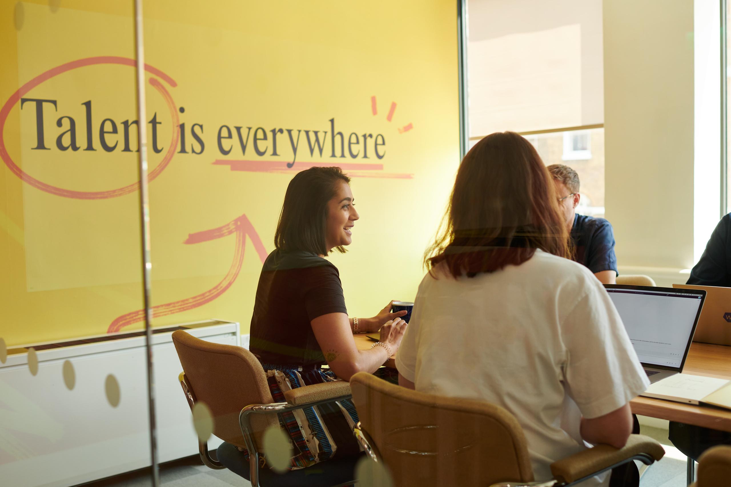 Woman in a meeting room talking with two other employees