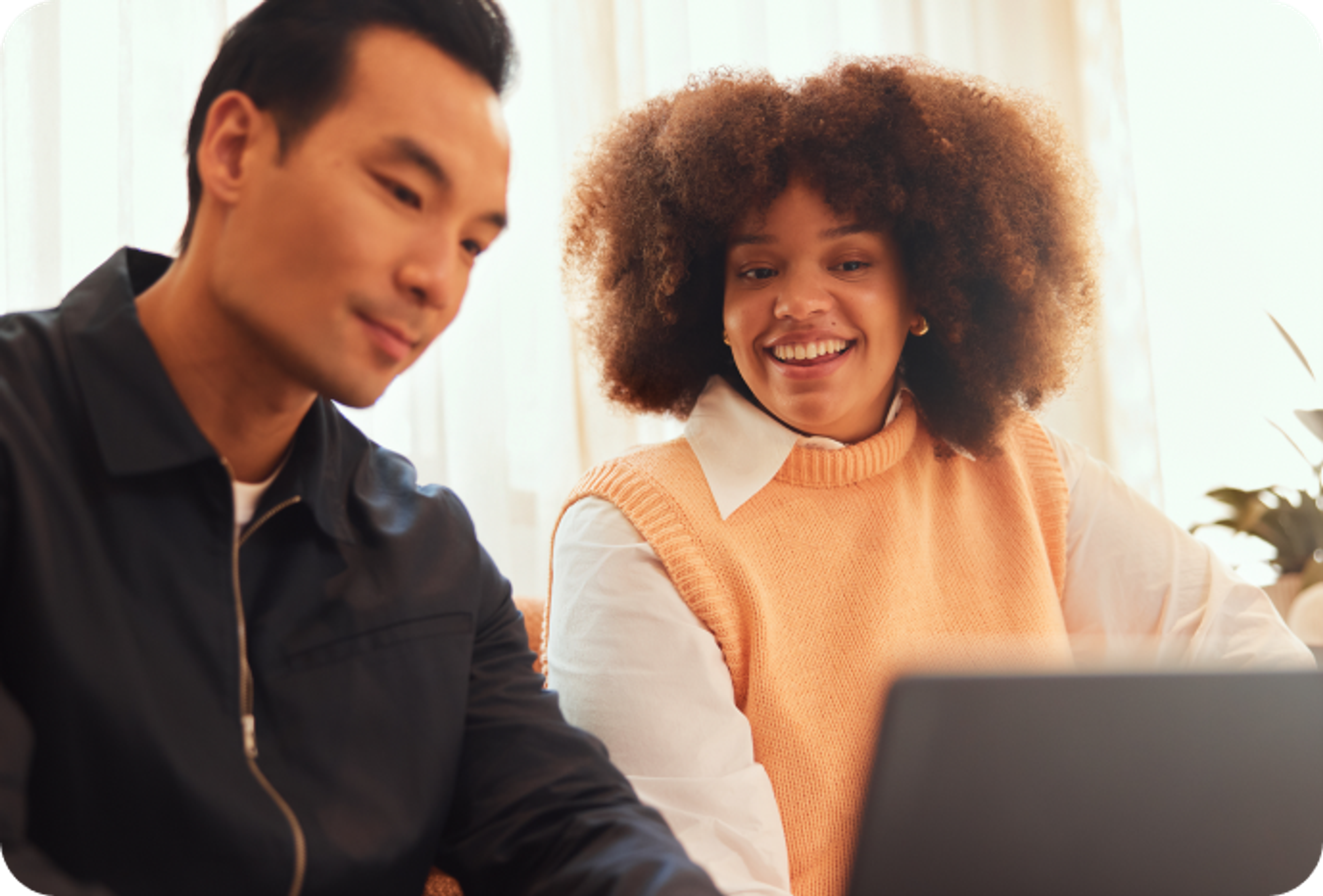 One colleague on a laptop and another sitting beside them