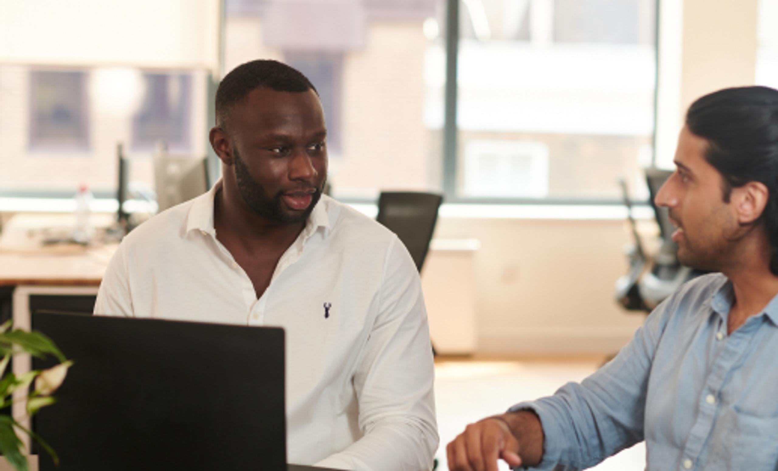 Two men talking at a laptop