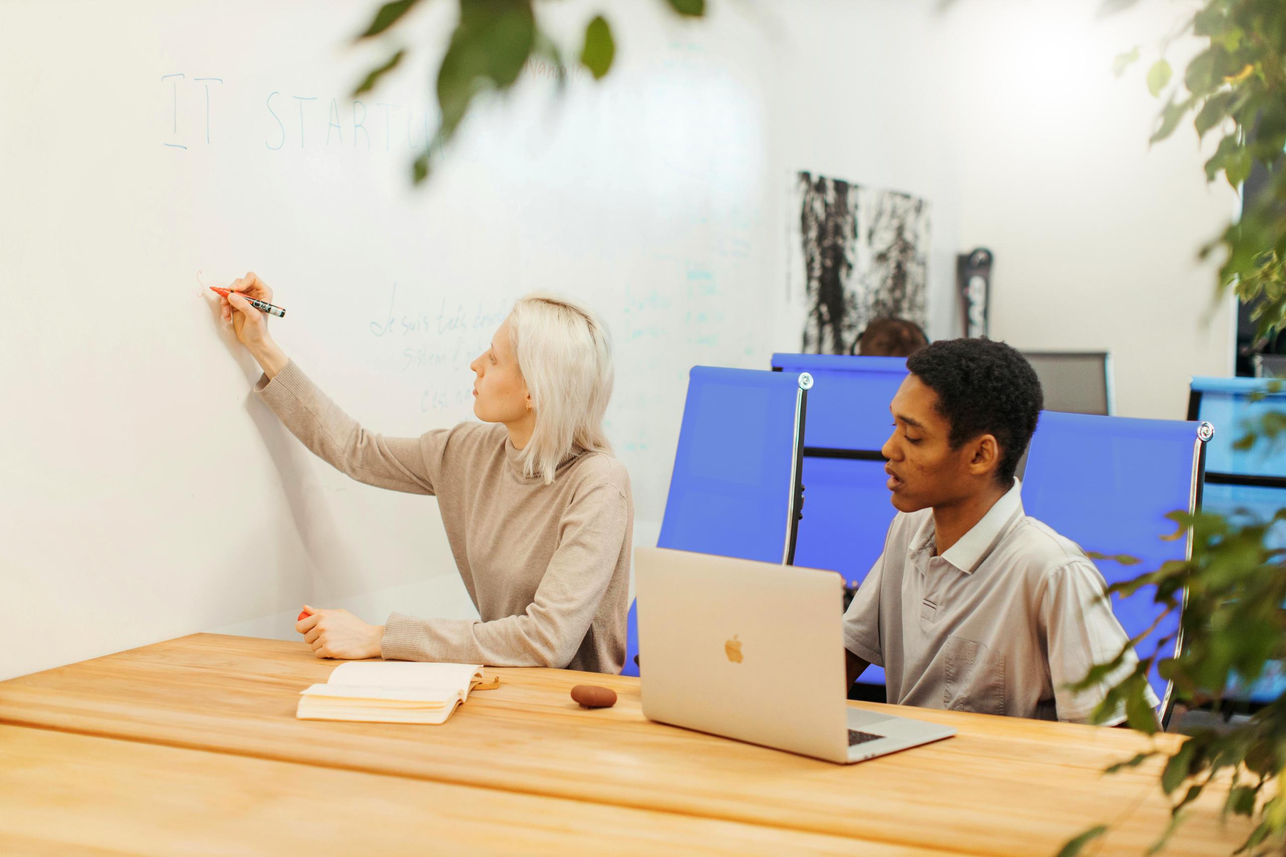 Two people writing on a whiteboard