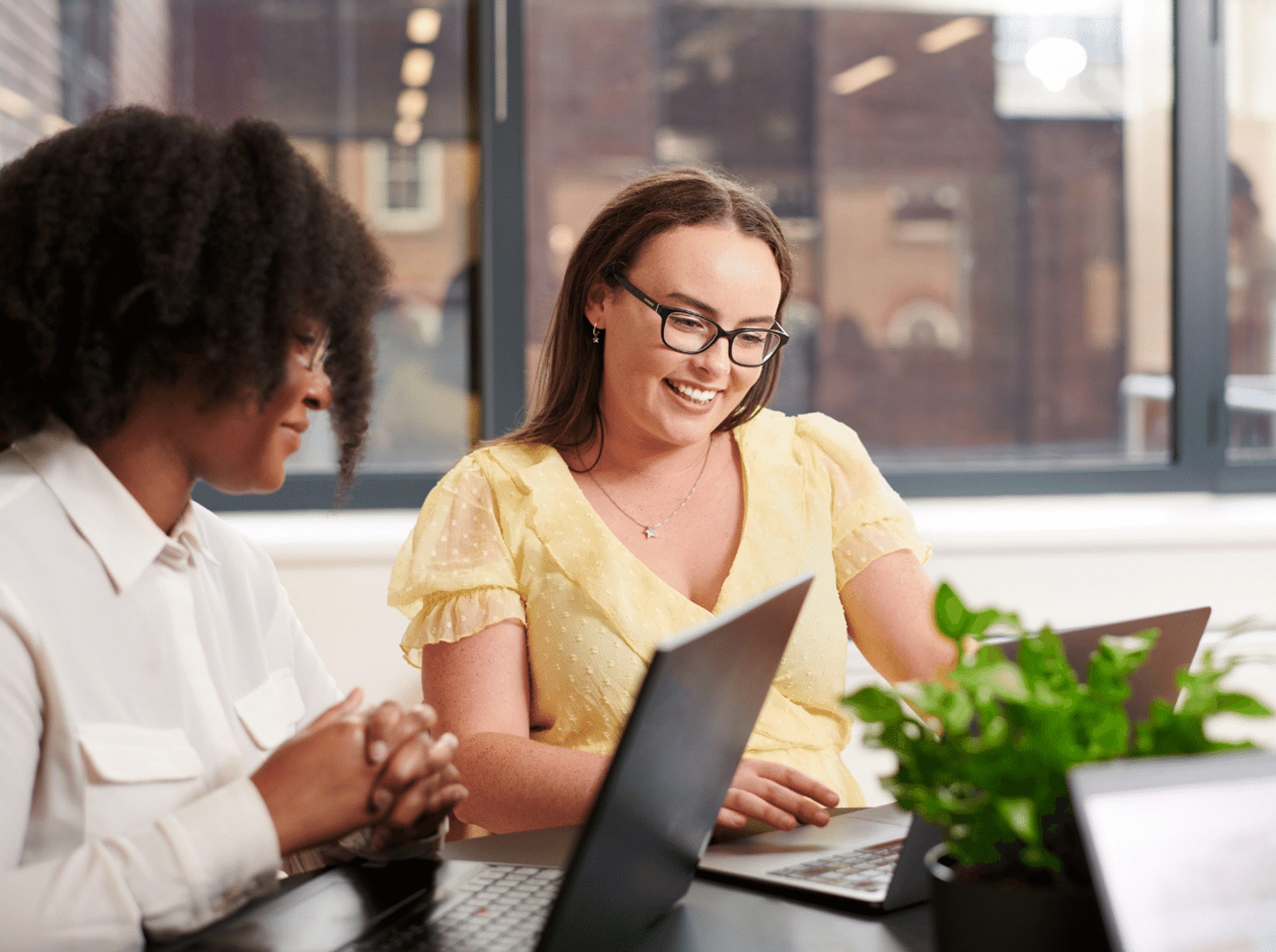 Two women smiling with laptops