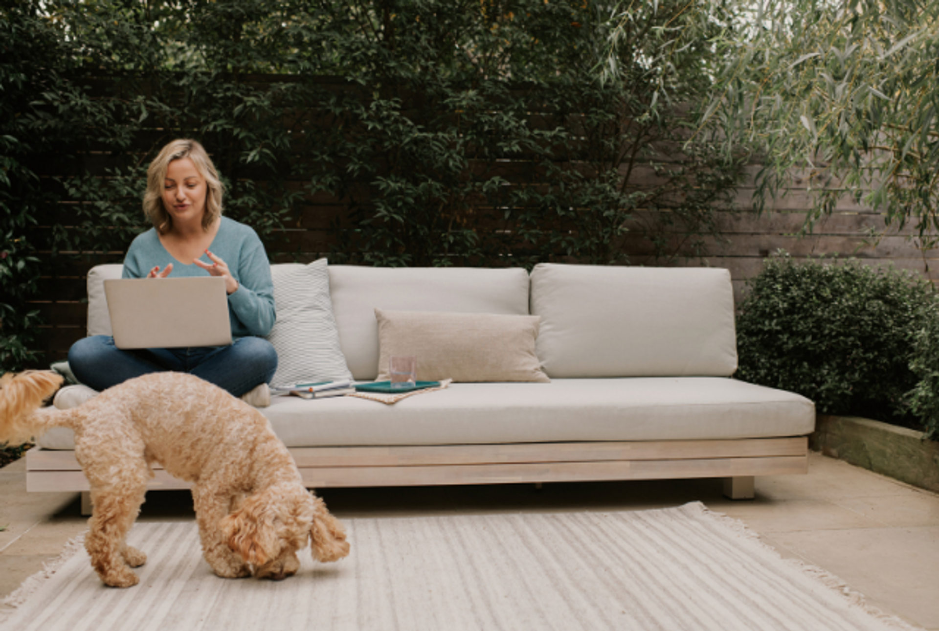 Woman working on her laptop in a garden with a dog 