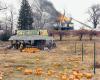 A firefighter picks out pumpkins in a field while a house is burning in the background