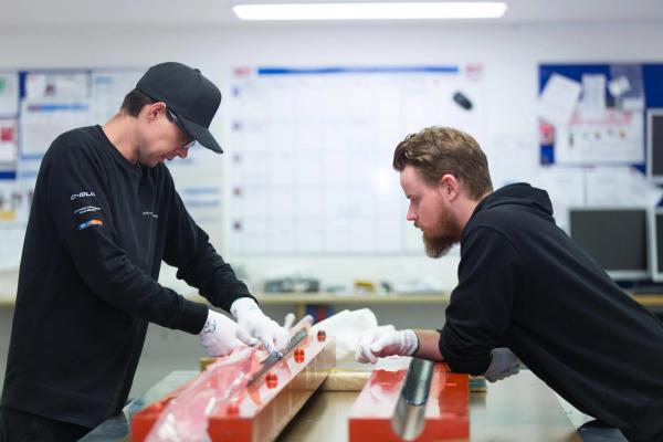 Aerial view of a serene tropical island with lush greenery surrounded by turquoise sea. Boats dot the water near the sandy shore, under a clear sky.