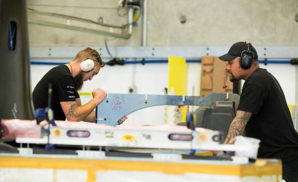 Aerial view of a serene tropical island with lush greenery surrounded by turquoise sea. Boats dot the water near the sandy shore, under a clear sky.