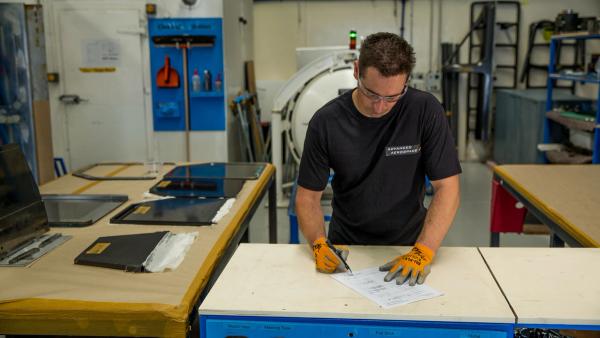 Aerial view of a serene tropical island with lush greenery surrounded by turquoise sea. Boats dot the water near the sandy shore, under a clear sky.
