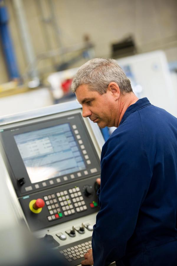 Aerial view of a serene tropical island with lush greenery surrounded by turquoise sea. Boats dot the water near the sandy shore, under a clear sky.