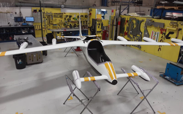 Aerial view of a serene tropical island with lush greenery surrounded by turquoise sea. Boats dot the water near the sandy shore, under a clear sky.