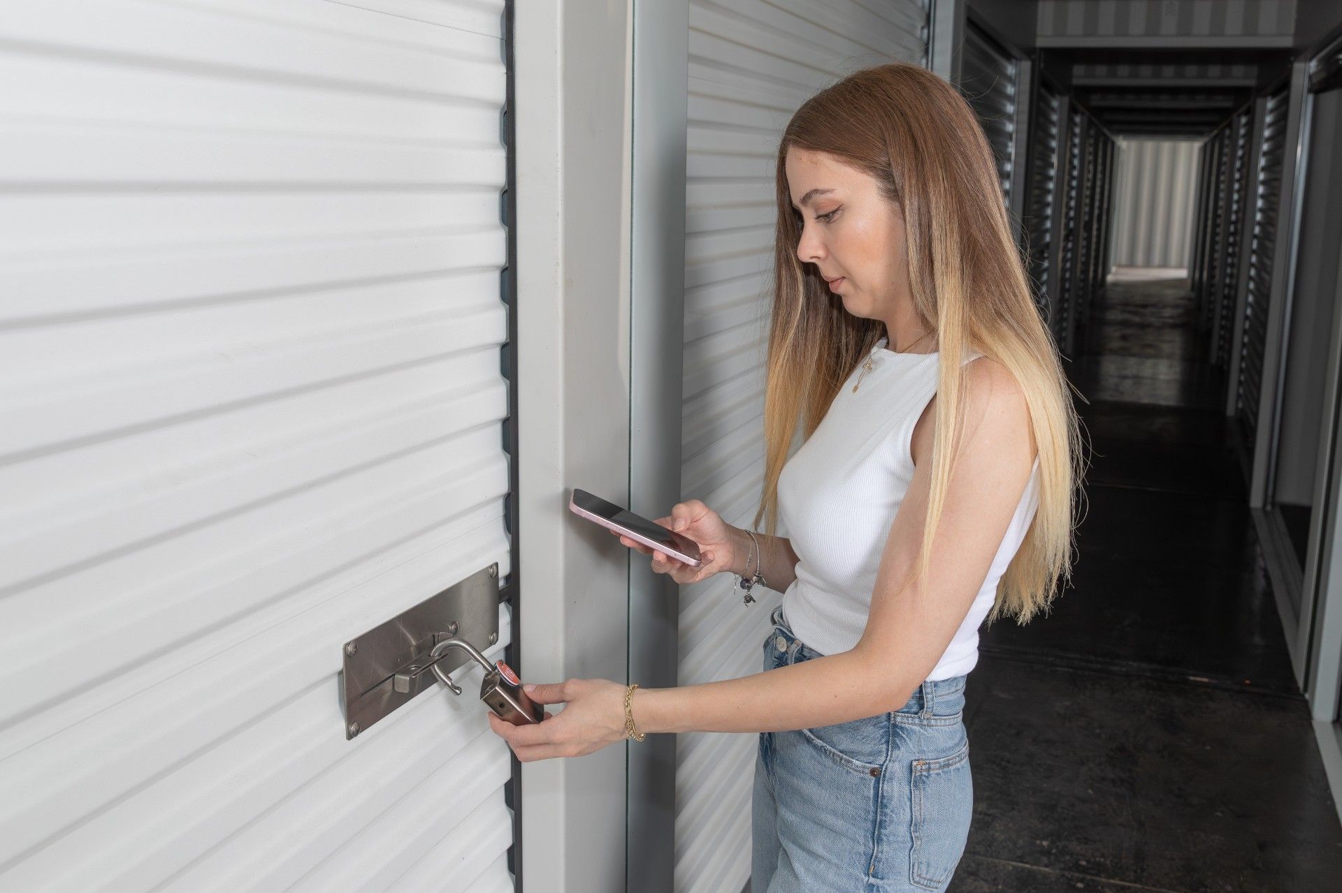 A self-storage tenant unlocking a smart padlock on a roller-door unit using a mobile app