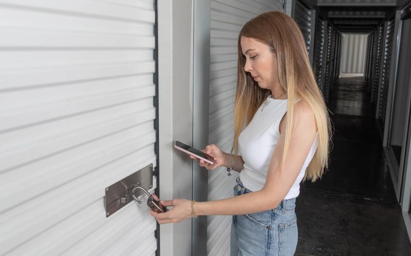 A self-storage tenant unlocking a smart padlock on a roller-door unit using a mobile app