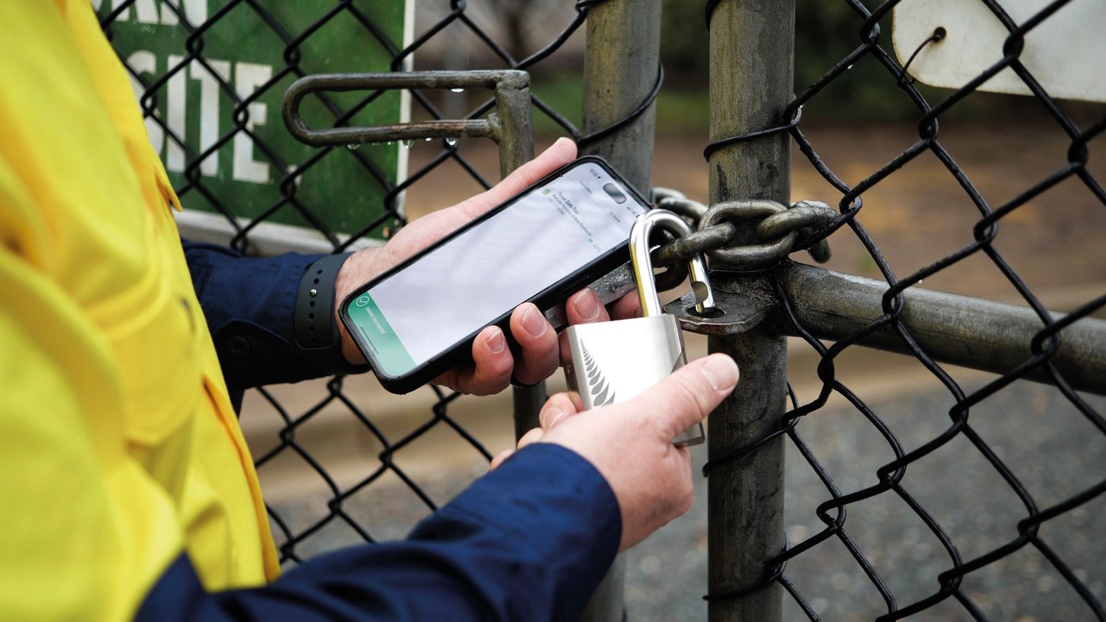 A field worker opening a Bluetooth smart padlock on a perimeter gate using a mobile app