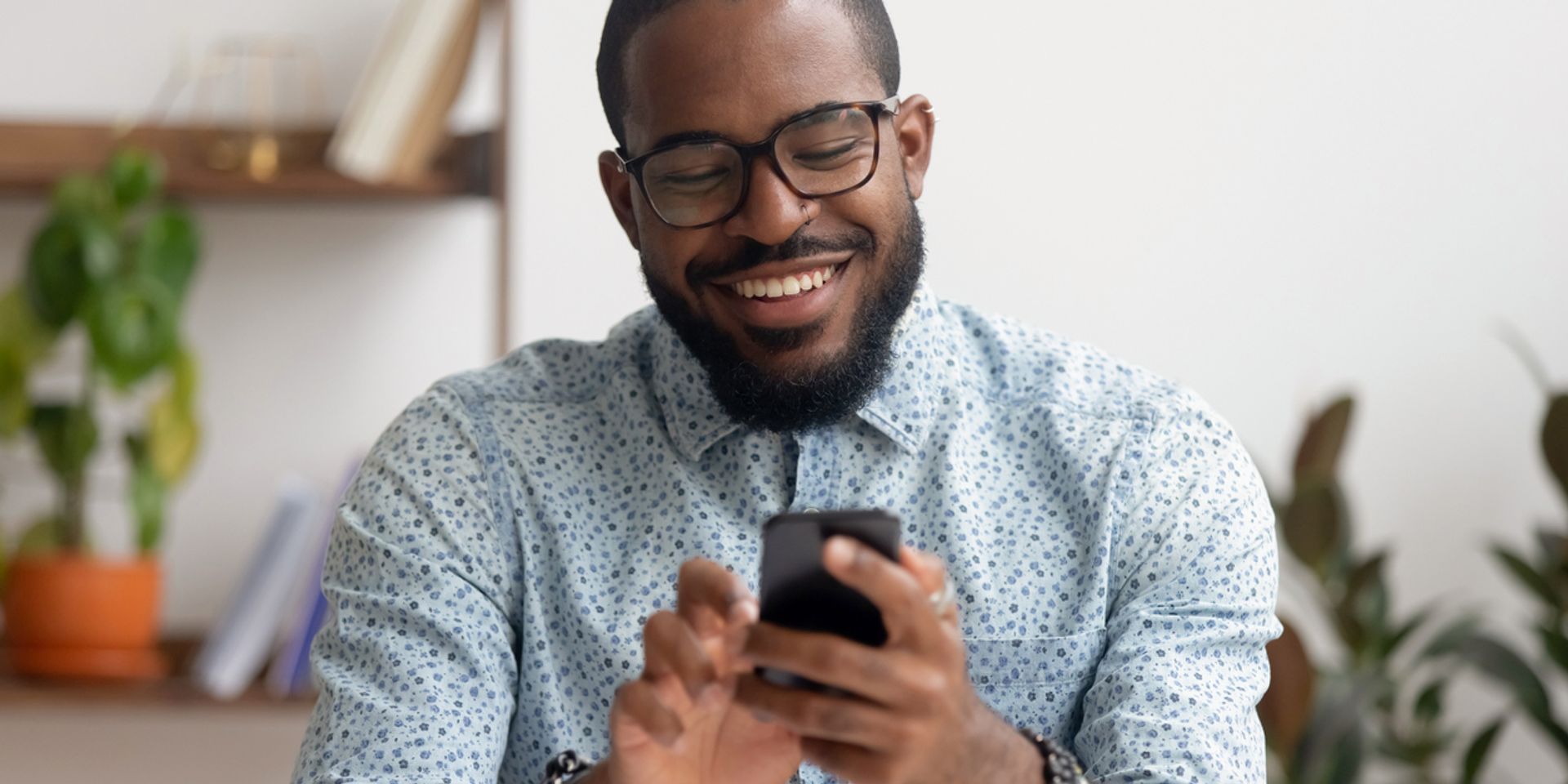 Black man typing on his phone and smiling
