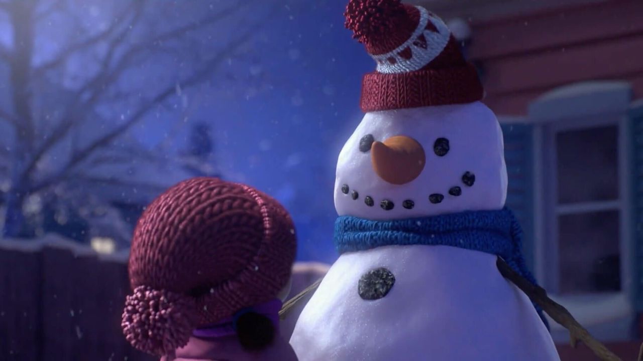 An animated image of a little girl looking at an adorable snowman outdoors.