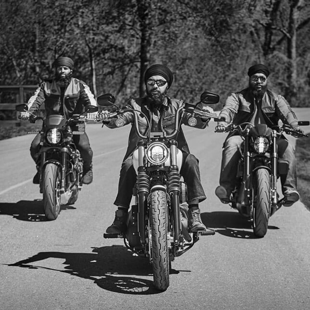 Three men wearing turbans riding Harley Davidson motorcycles, cruising confidently down the road.