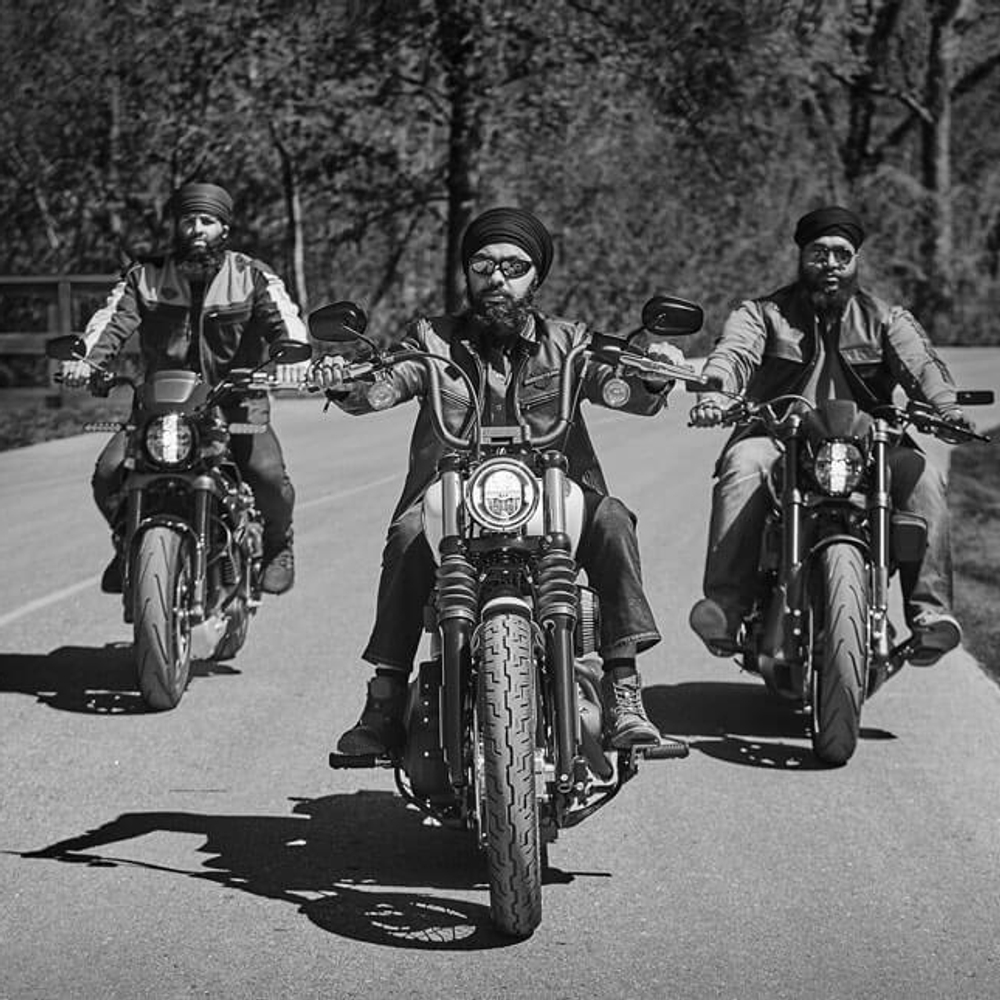 Three men wearing turbans riding Harley Davidson motorcycles, cruising confidently down the road.