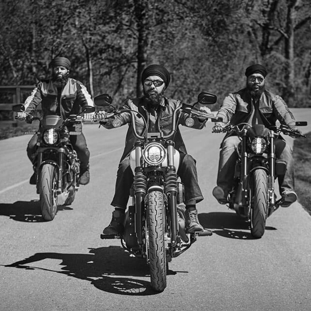 Three men wearing turbans riding Harley Davidson motorcycles, cruising confidently down the road.