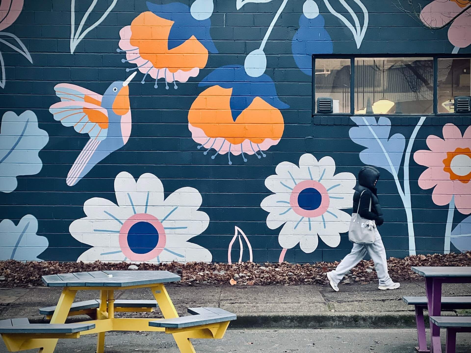 A person walking by a large mural of flowers in Vancouver