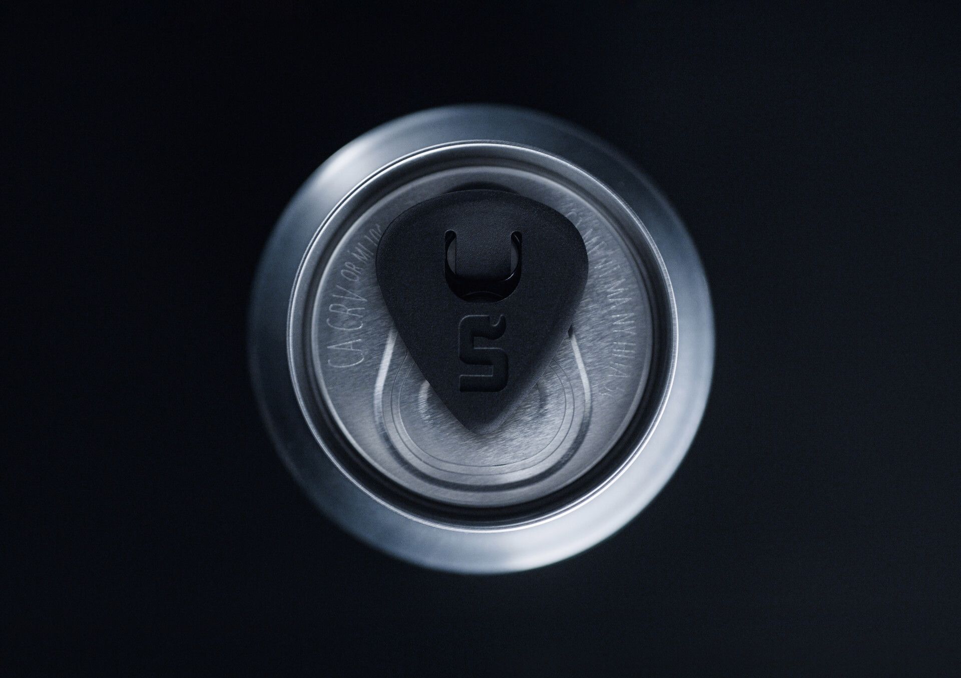 An overhead view of beer can with a guitar pick where the pull tab would be.